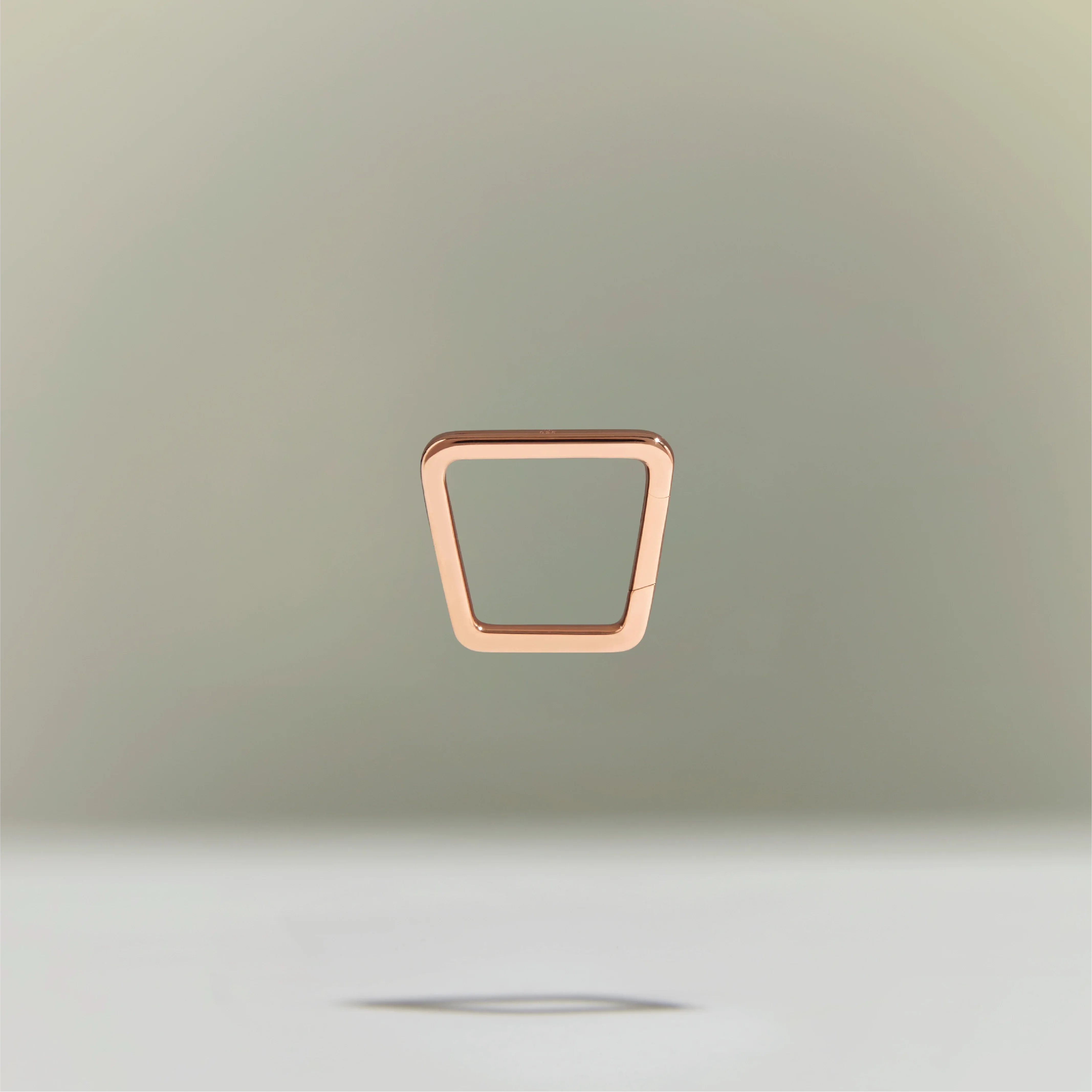 Minimalist rose gold trapezoid-shaped ring floating above a neutral background.