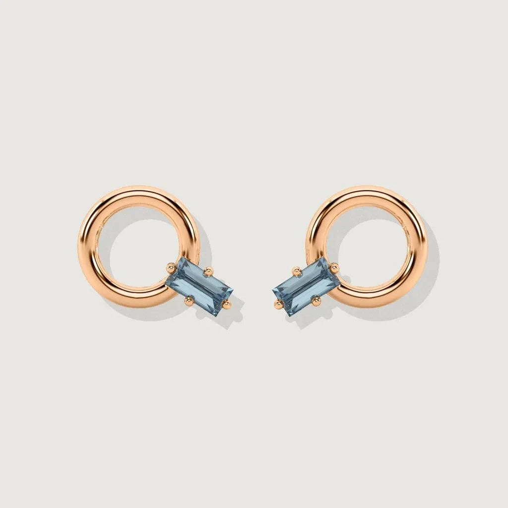 Pair of rose gold hoop stud earrings with rectangular blue gemstones on white background.