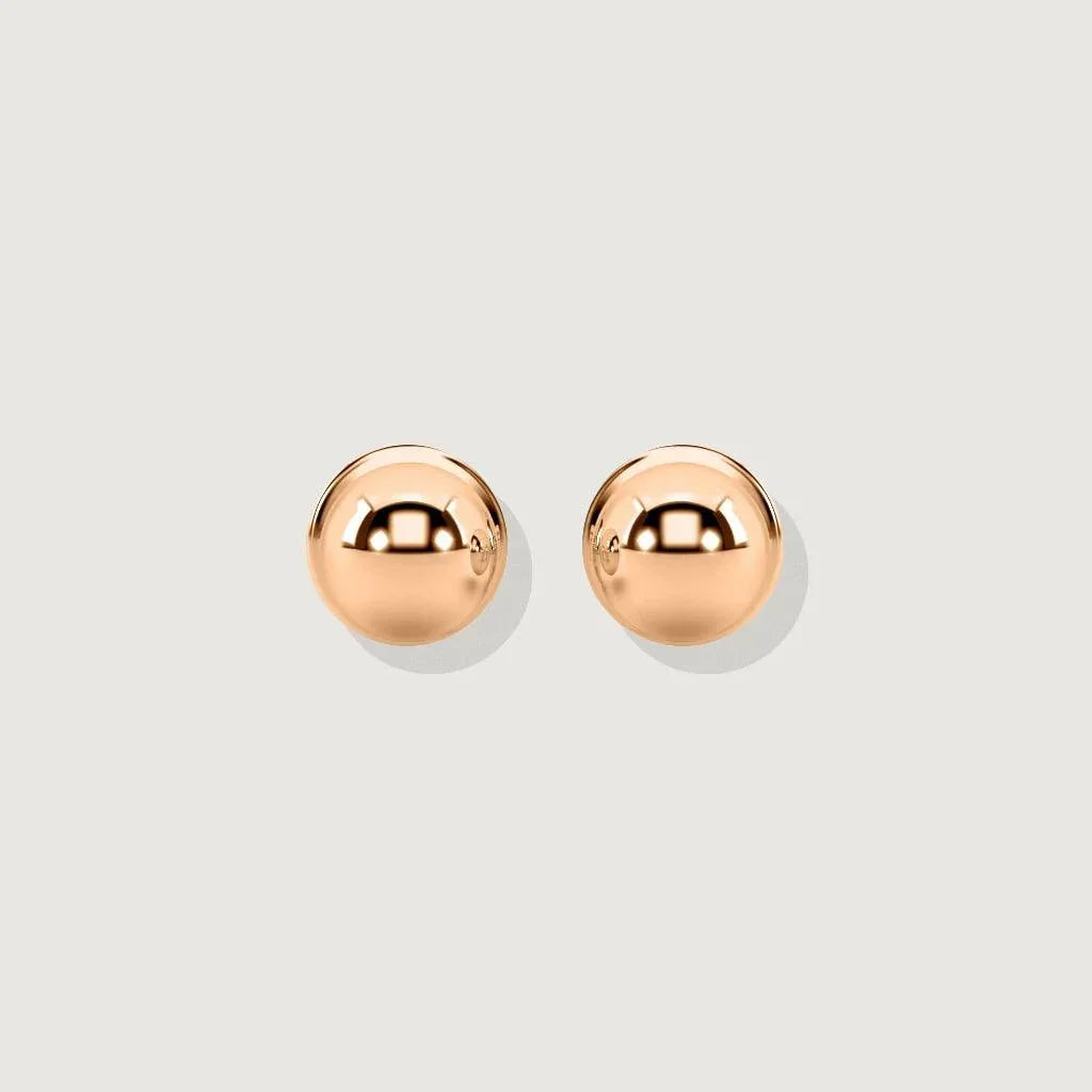 Product shot of a pair of polished rose gold ball stud earrings on a light grey background. The earrings are perfectly spherical and highly reflective.