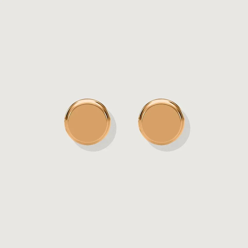 Product shot on light background of a pair of simple, polished, flat, round rose gold stud earrings.