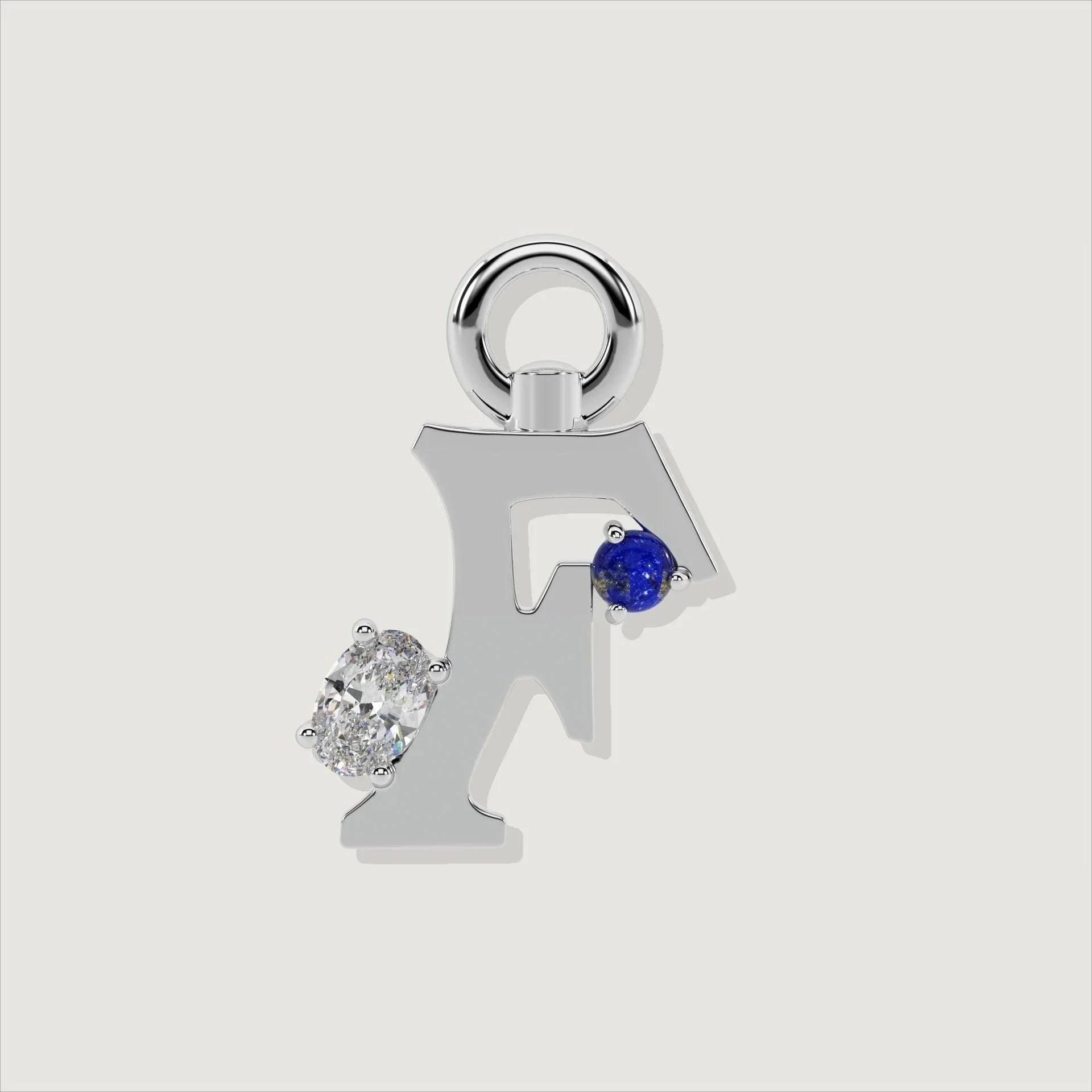 Silver letter F charm adorned with a round blue lapis and oval clear stone.