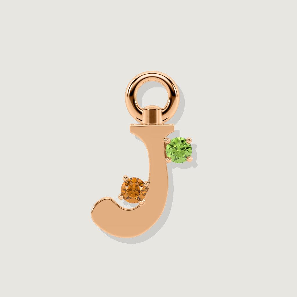Rose gold letter J charm with round orange and green gemstones.