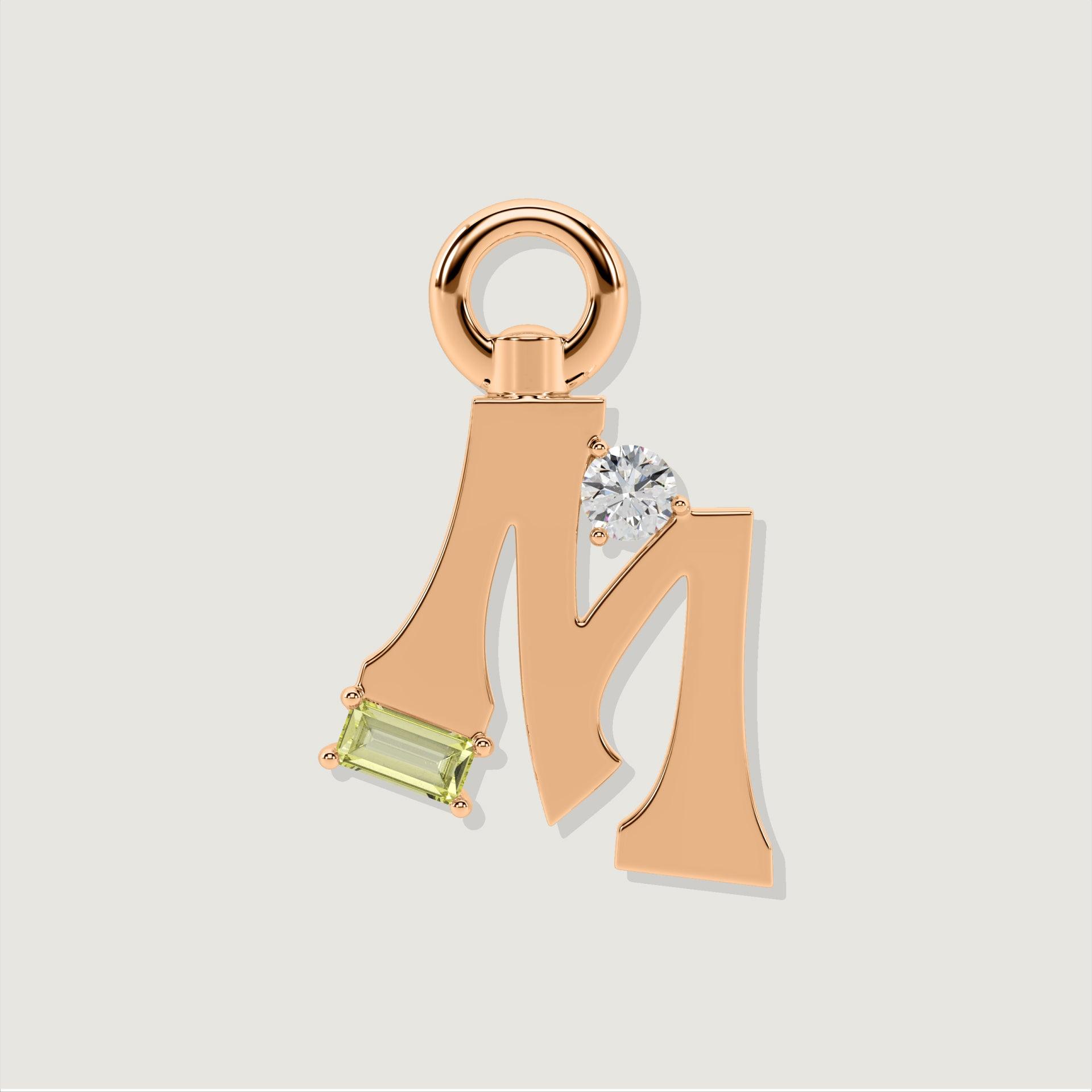 Rose gold letter M charm adorned with a clear round gemstone and a rectangular pale green gemstone.