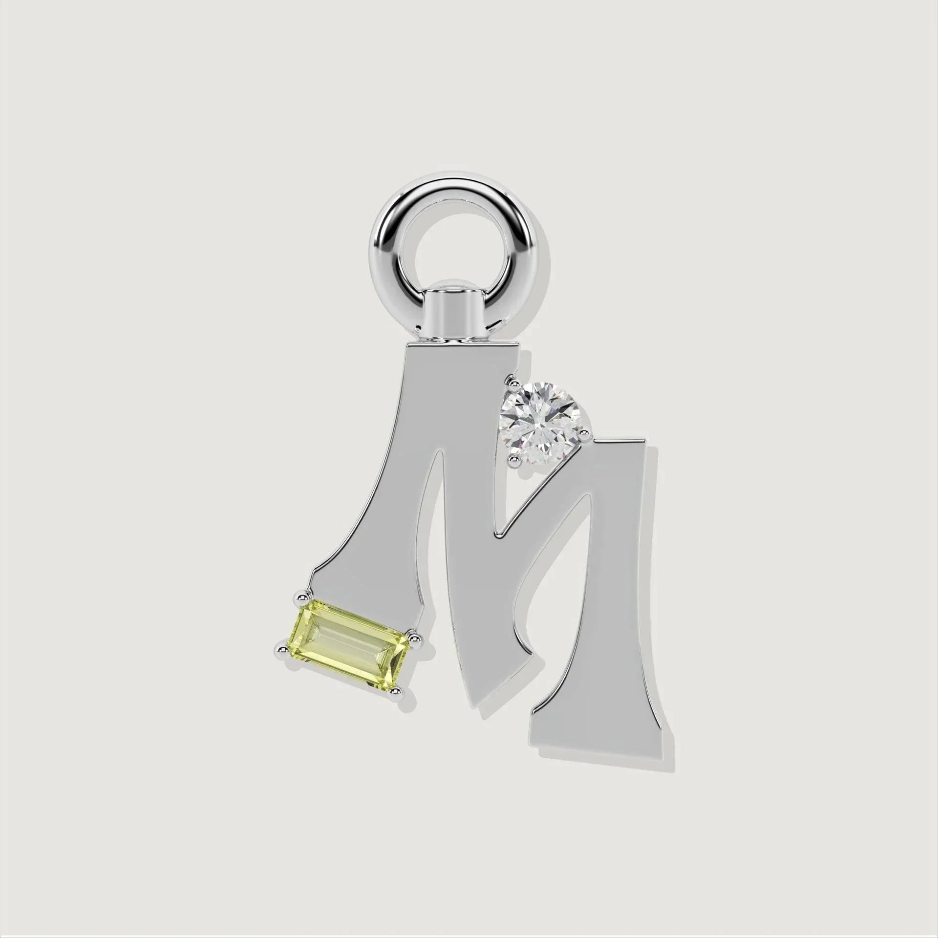 Silver letter M charm adorned with a clear round gemstone and a rectangular pale green gemstone.