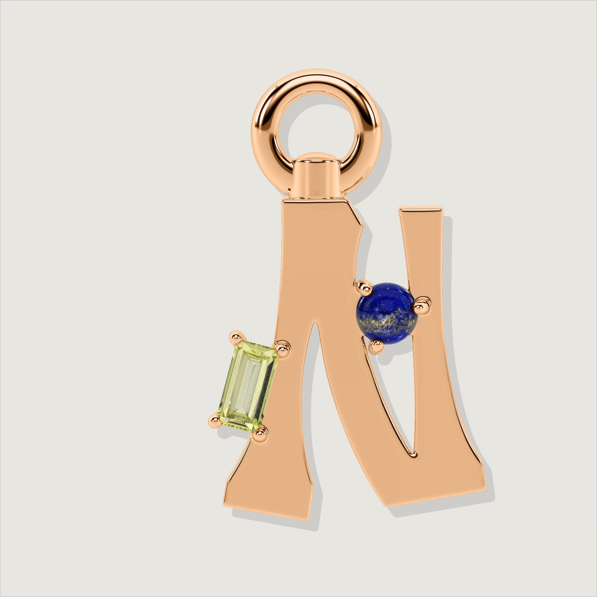 Rose gold letter N charm with a yellow baguette-cut gem and a round lapis-blue stone.