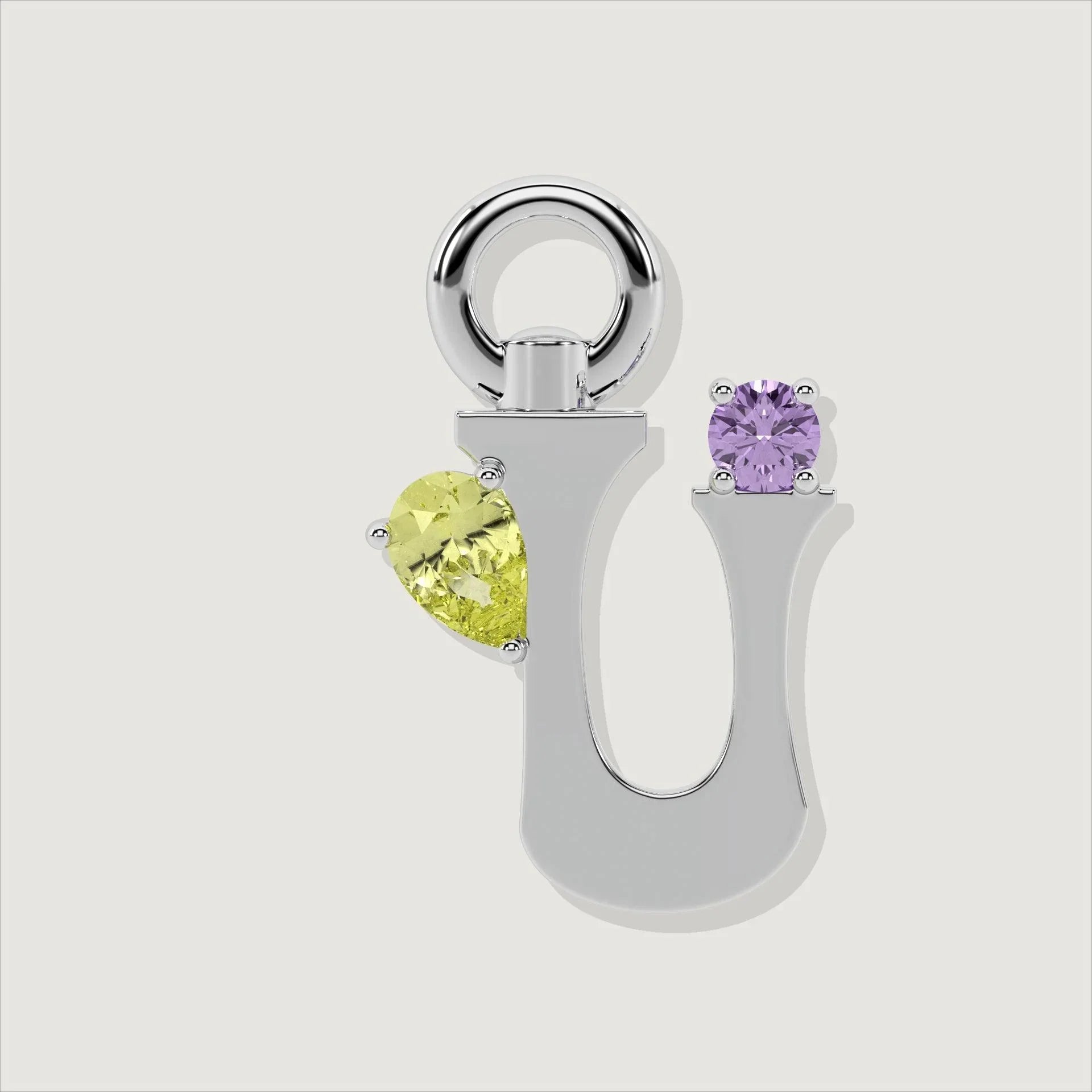 Silver letter U charm adorned with a pear-cut yellow gemstone and a round purple gem.