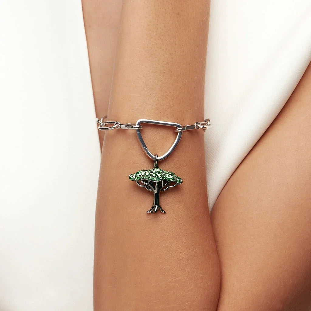 Silver chain bracelet featuring a green gemstone tree charm.