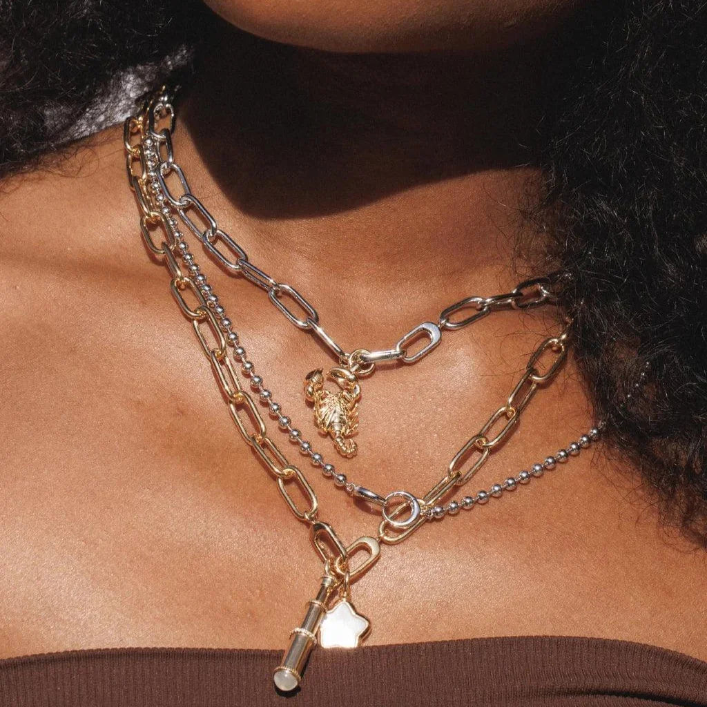 Layered mixed-metal necklaces with scorpion, star and telescope charms