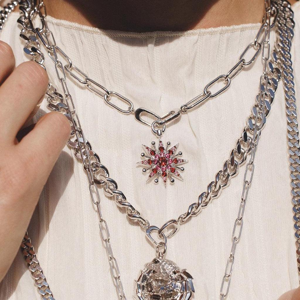 Layered silver necklaces featuring a red starburst charm and a detailed dragon pendant