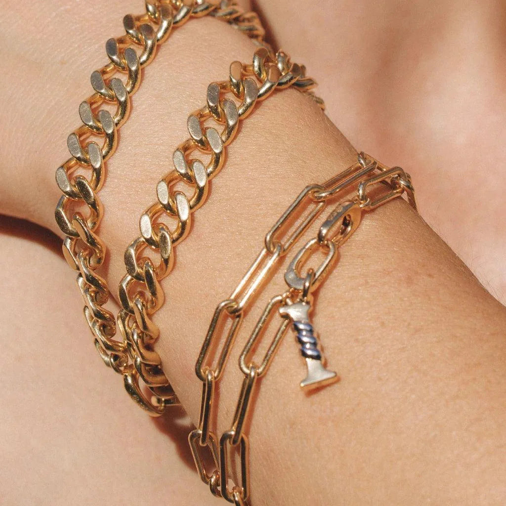 Stacked gold bracelets with letter charm on chain link band.