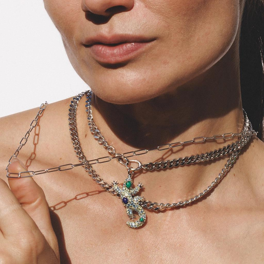 Layered silver chains with gemstone lizard pendant worn as statement necklace