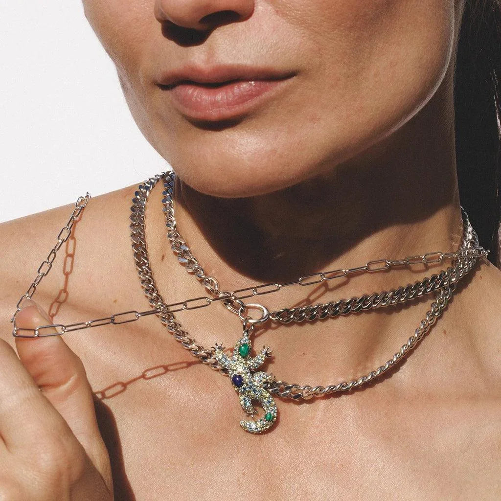 Layered silver chains with gemstone lizard pendant worn as statement necklace