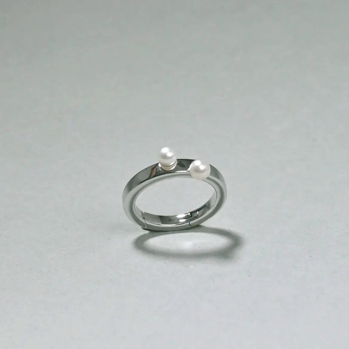 Silver ring with two pearls on a gray background