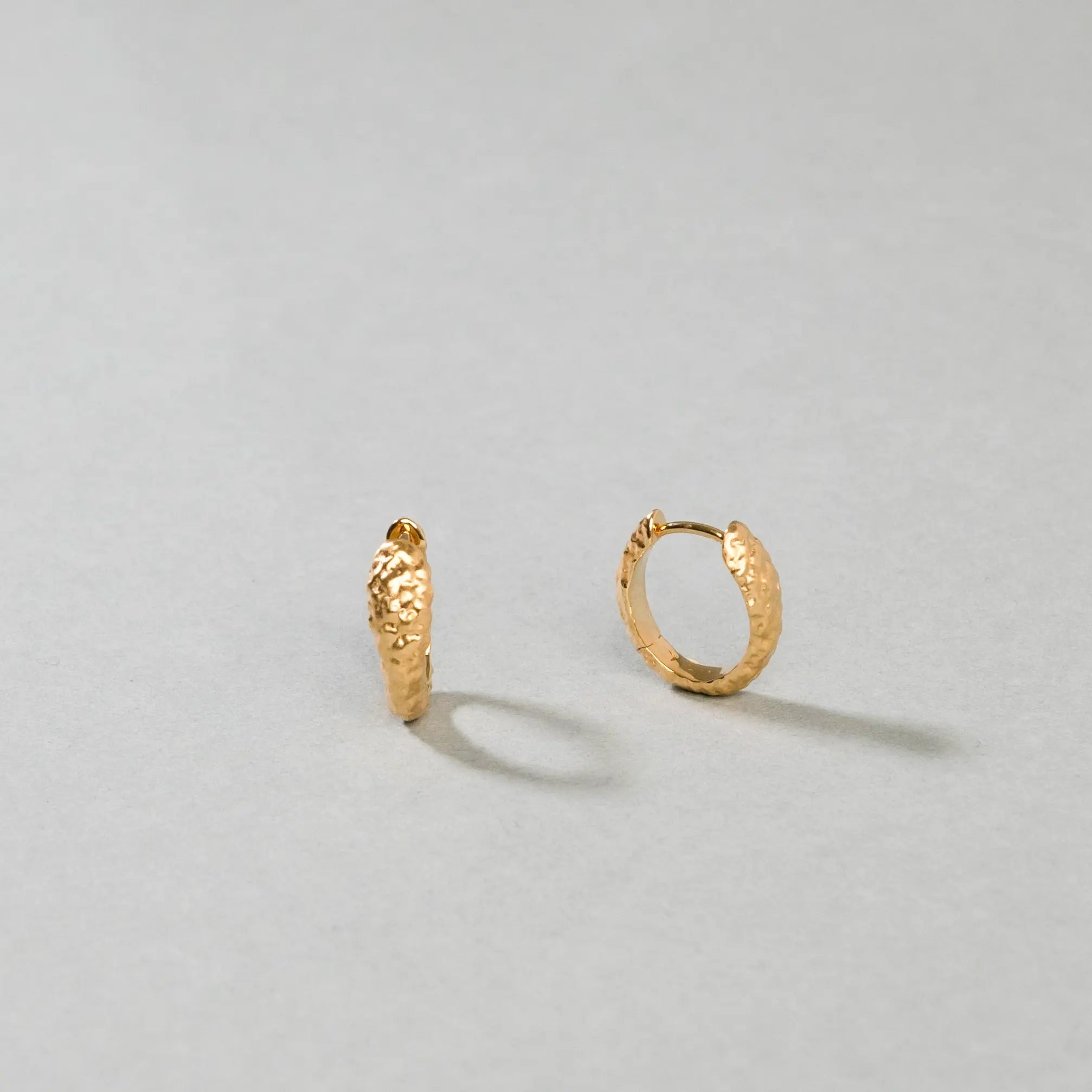 Gold hoop earrings on a light gray background