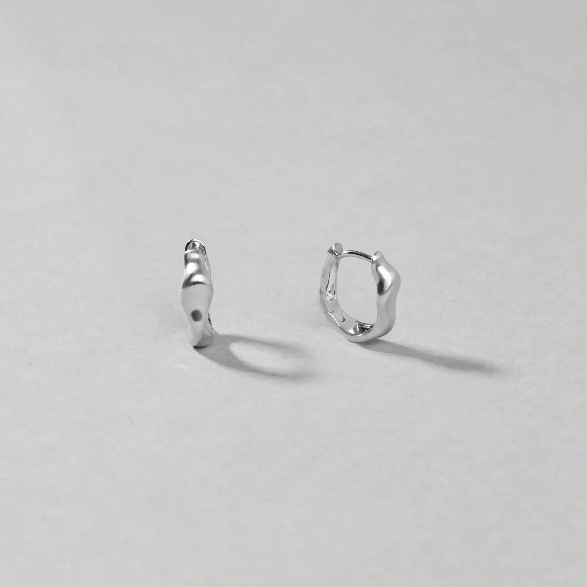 Pair of silver hoop earrings on a light gray background