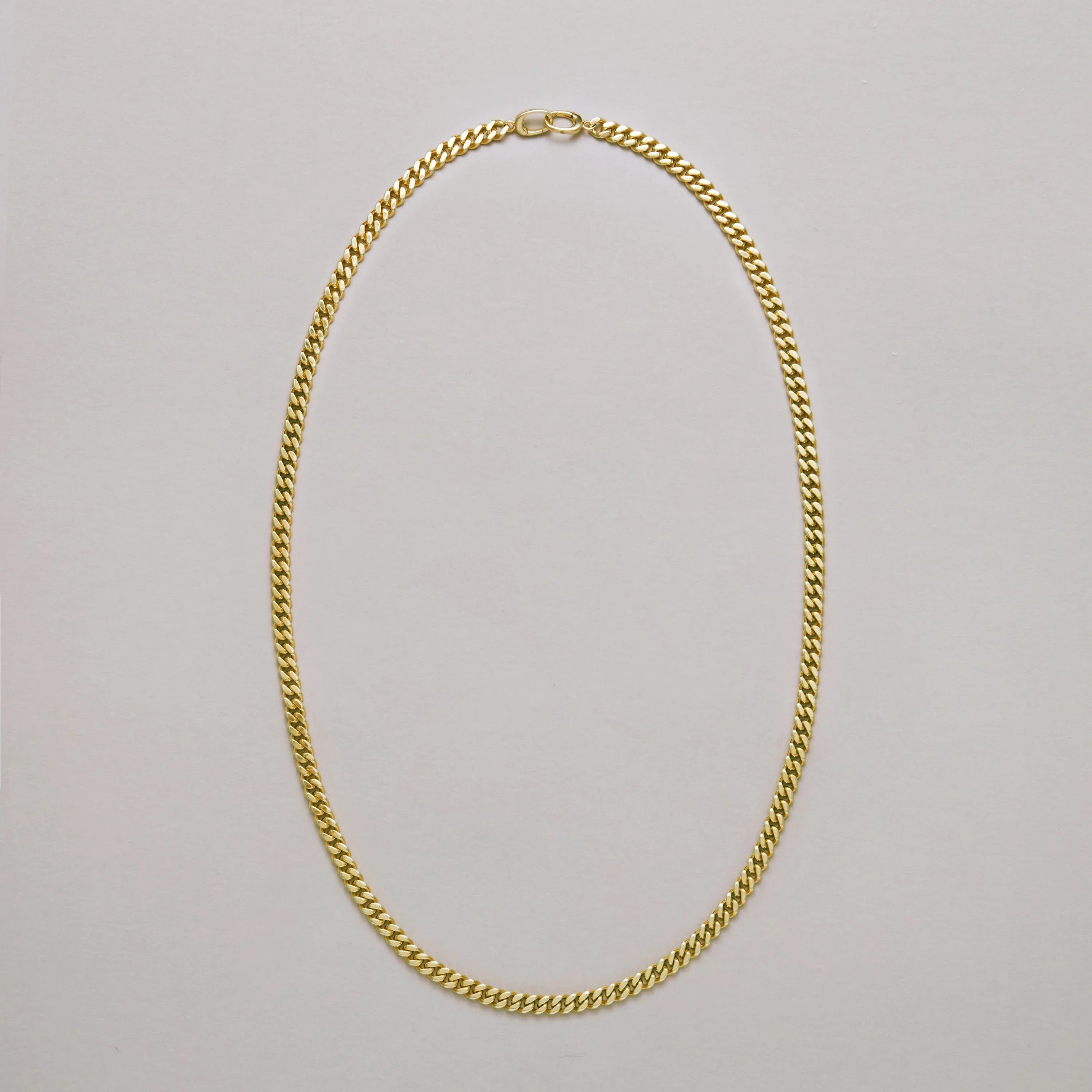 Gold curb chain necklace displayed on neutral background.