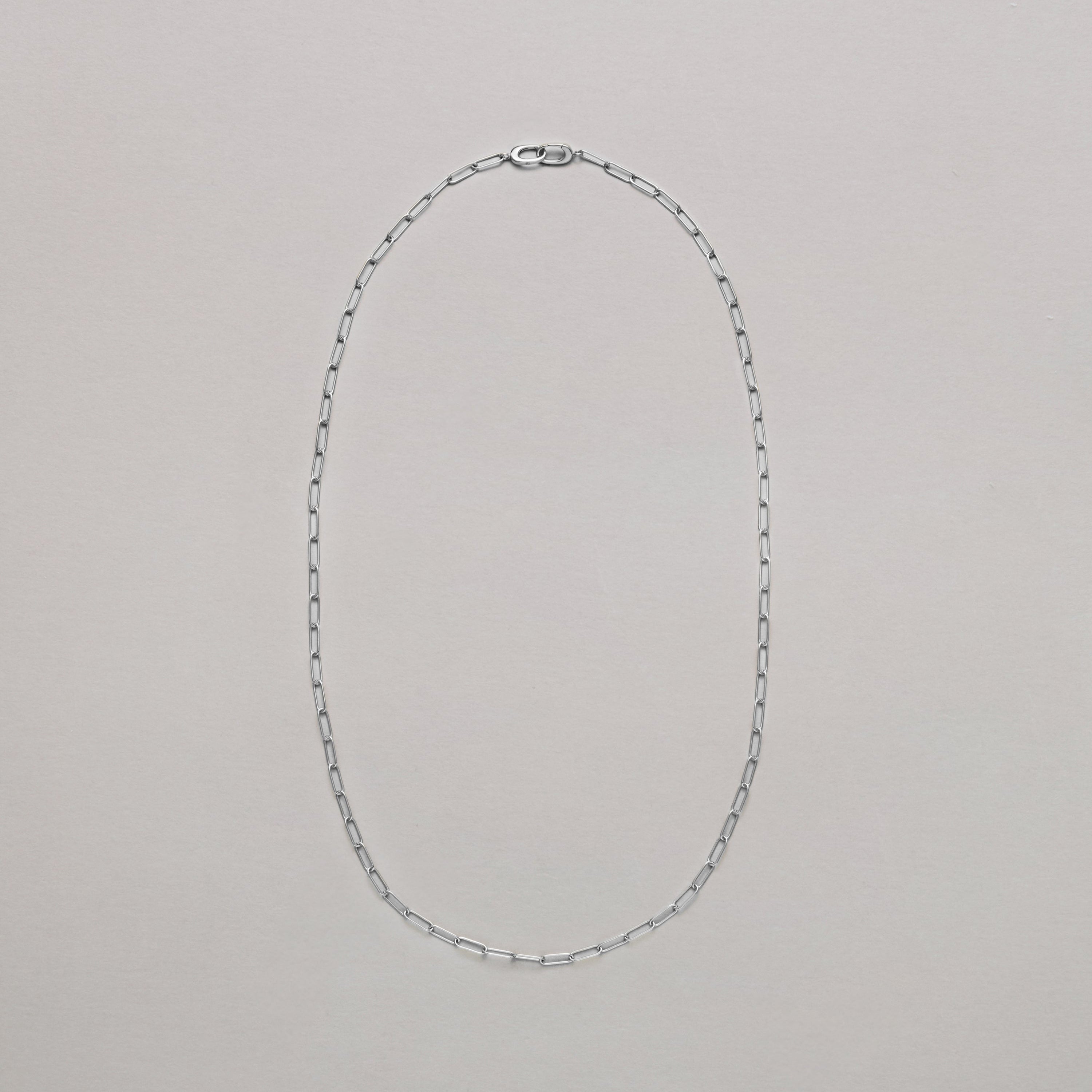 Classic silver paperclip chain necklace laid flat on neutral background.