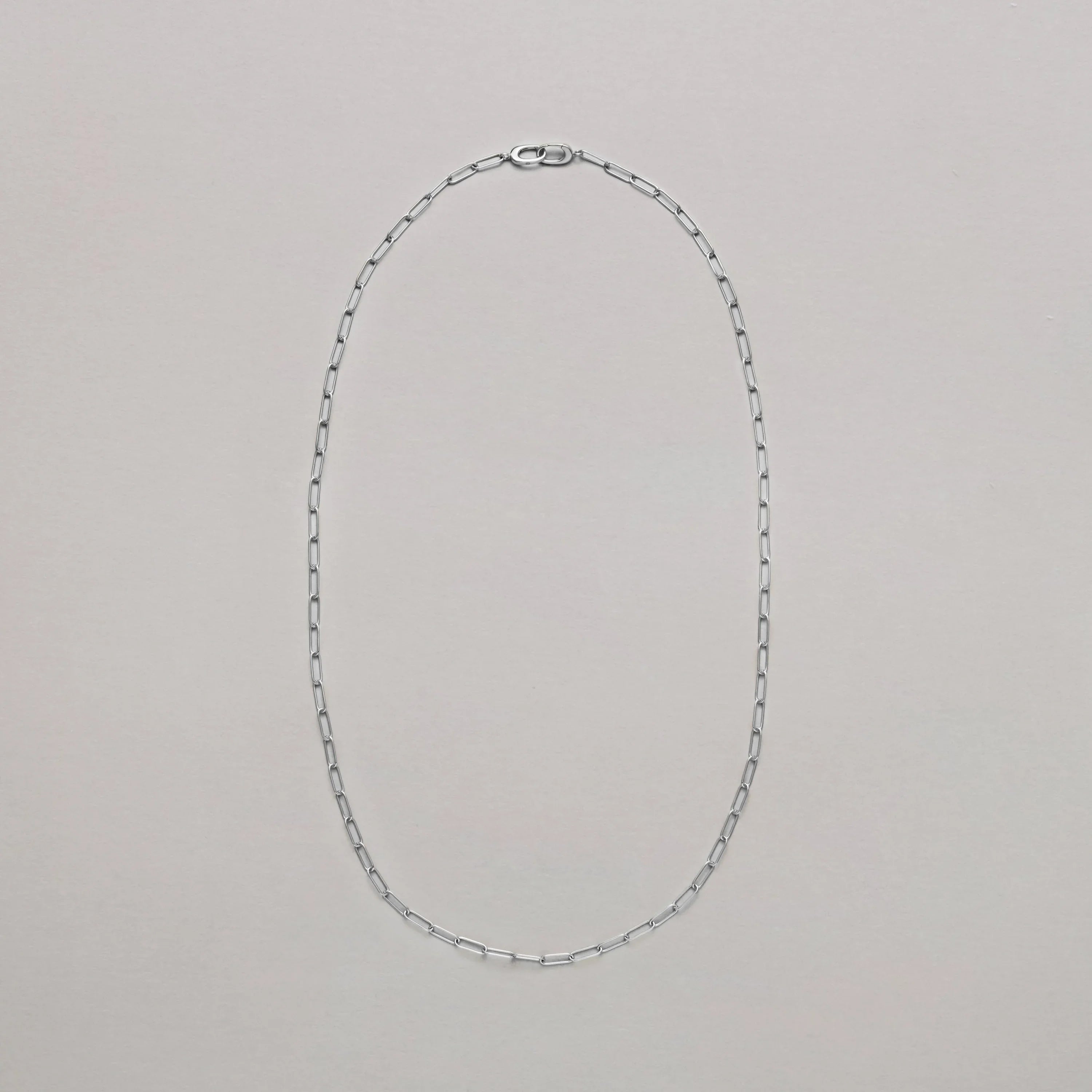 Classic silver paperclip chain necklace laid flat on neutral background.