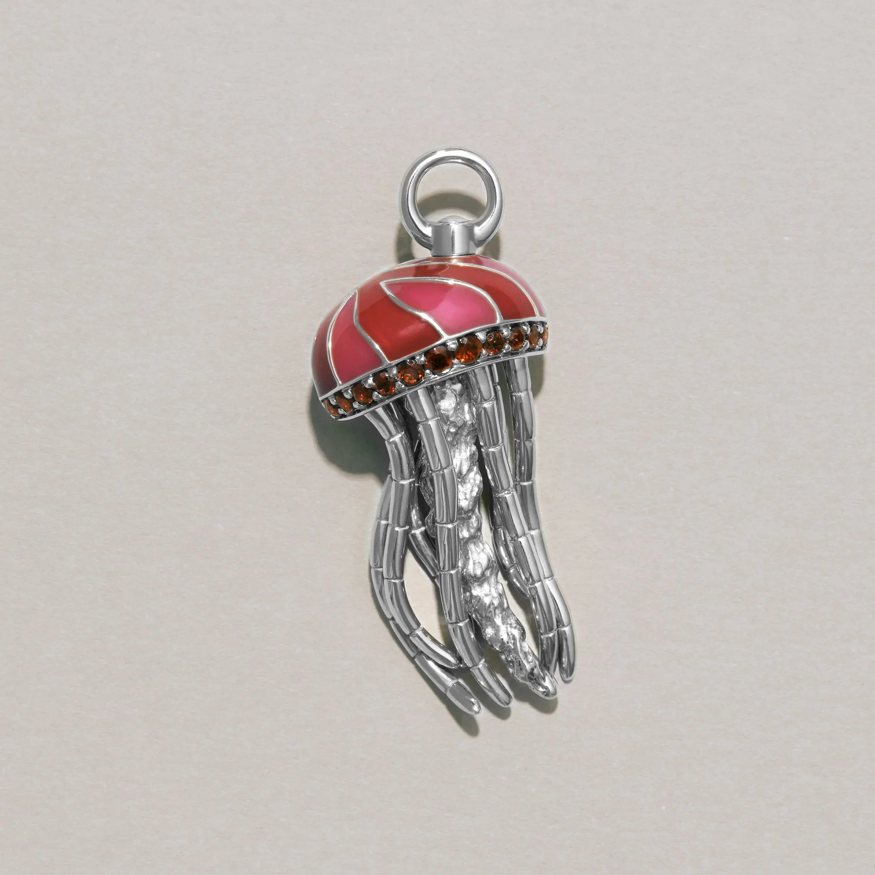 Jellyfish-shaped charm with red top and silver body on a light gray background