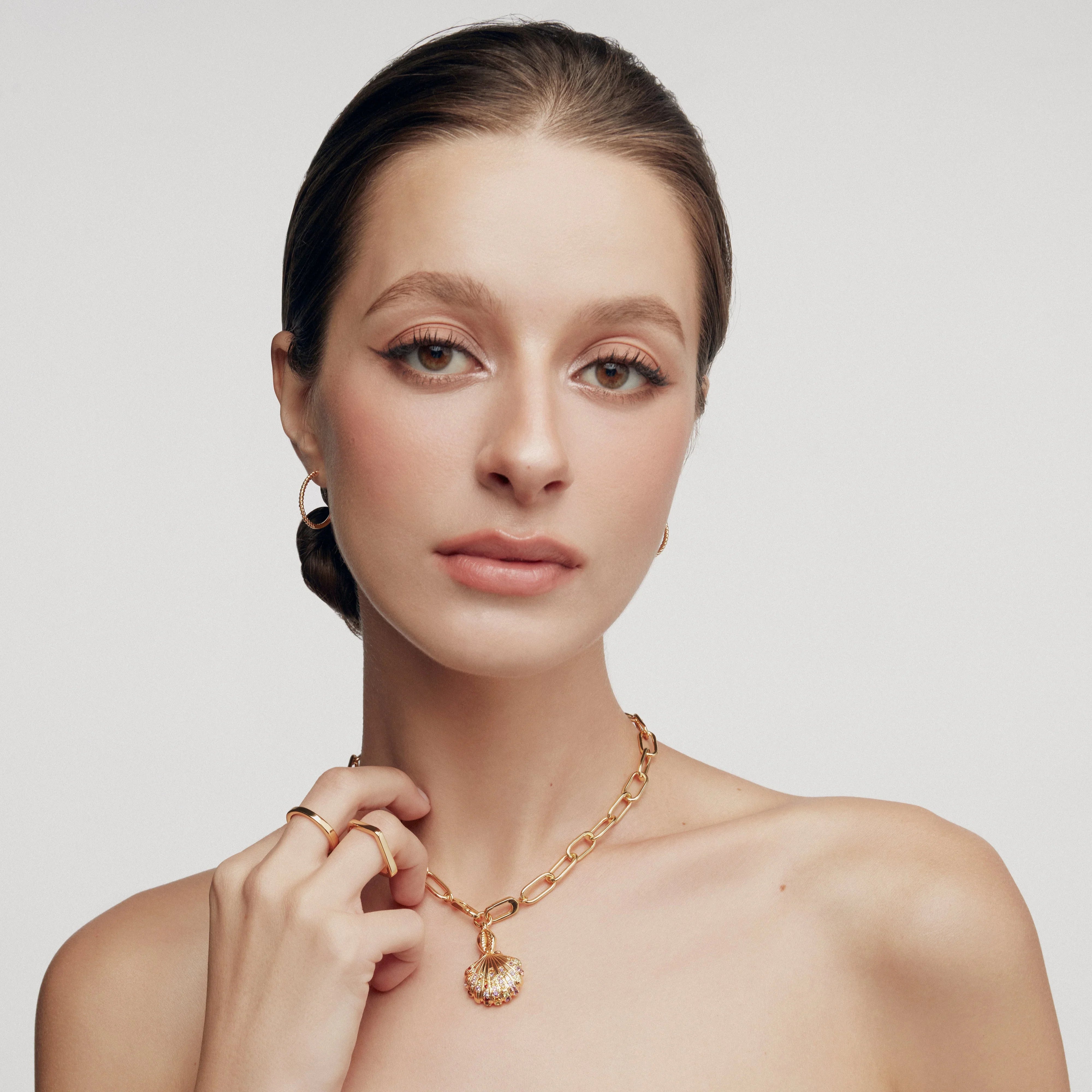 Elegant woman modeling a chunky gold chain with a seashell charm