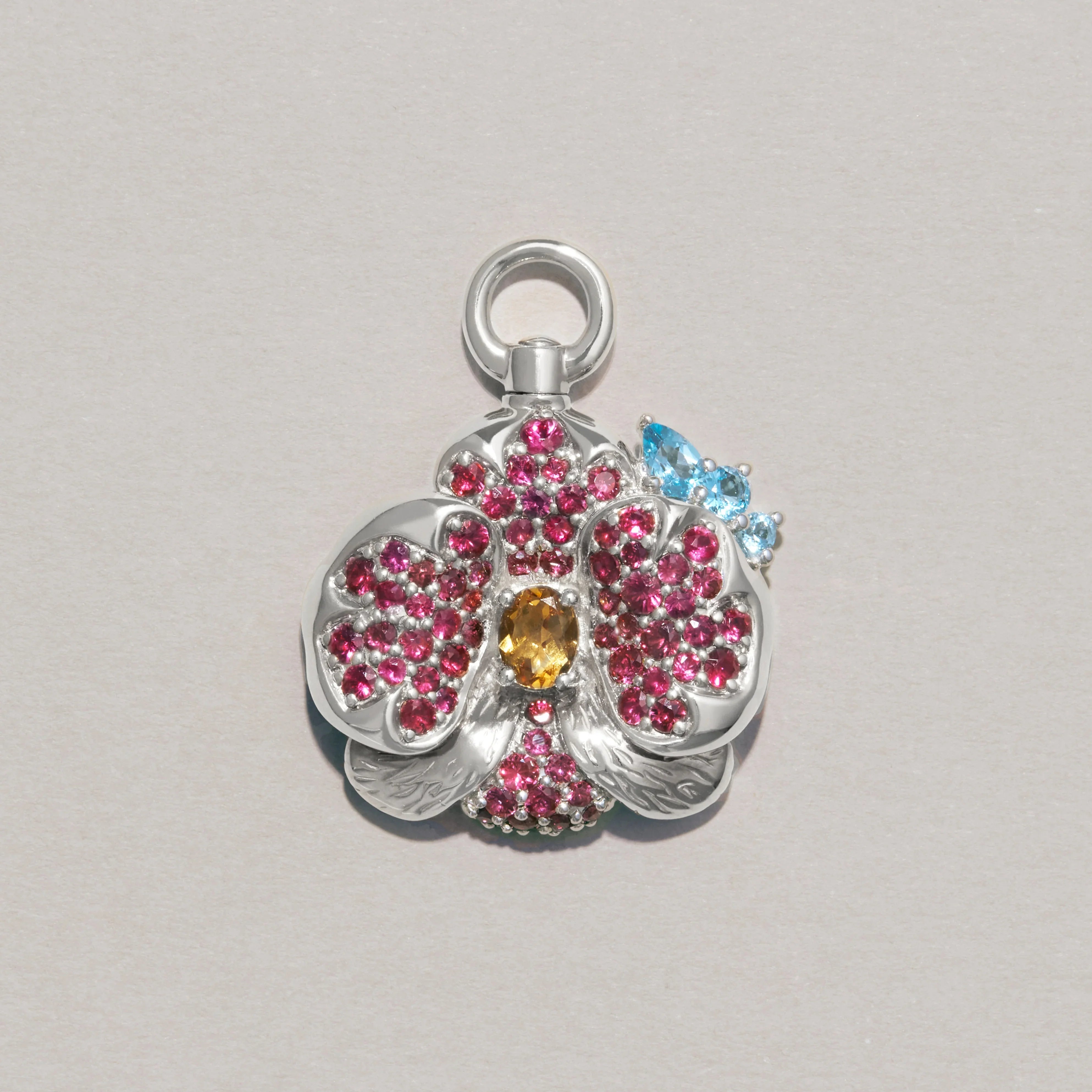 Silver flower charm with pink and blue gemstones on a light gray background