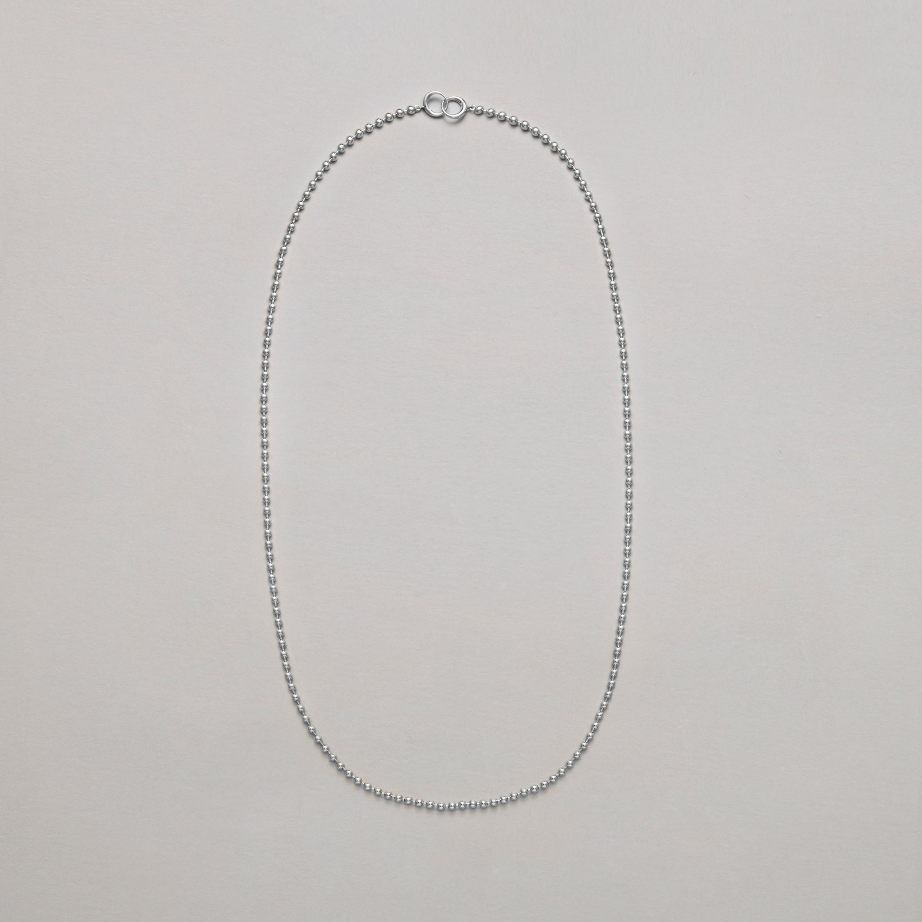 Long silver beaded chain necklace on a light gray background