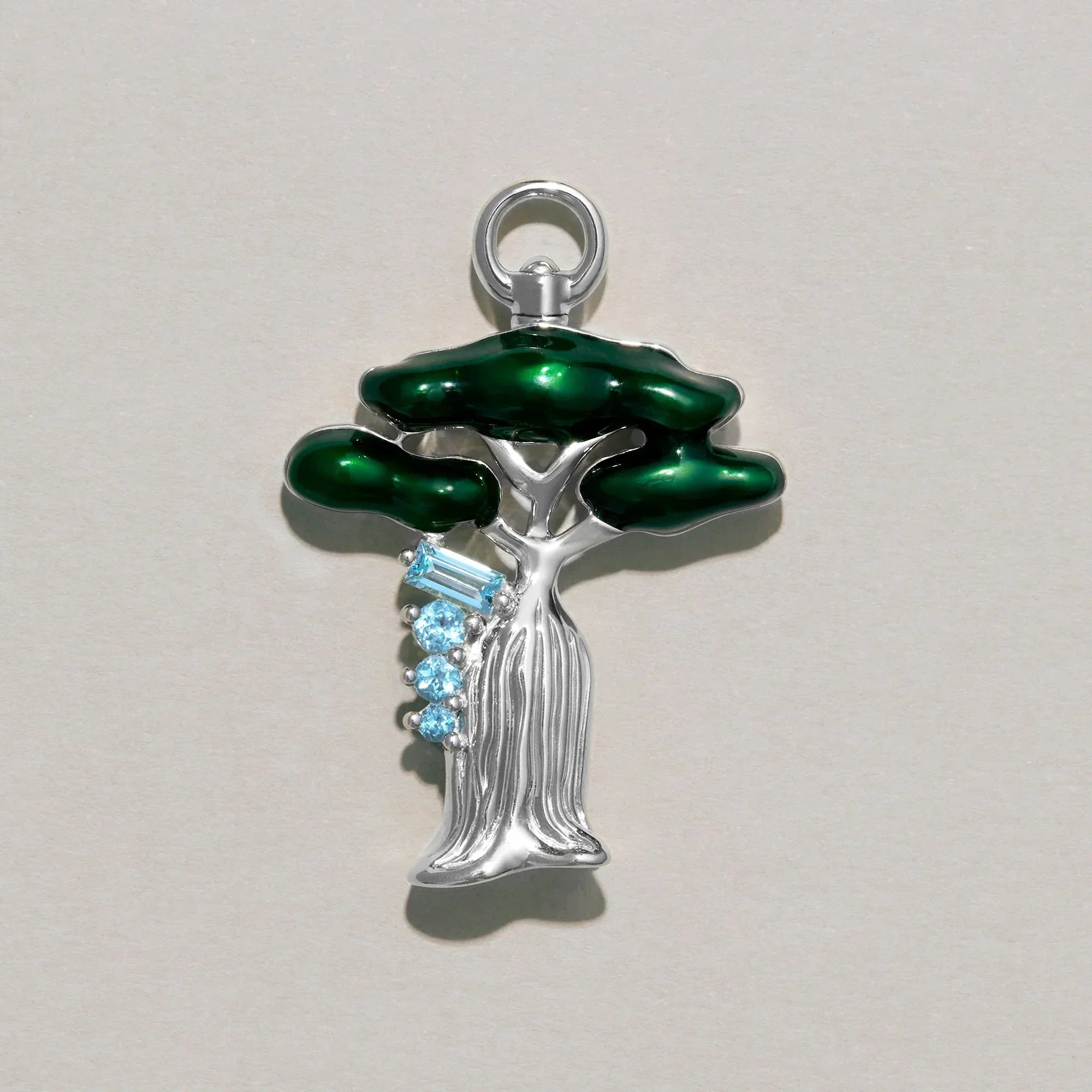 Tree-shaped pendant with green leaves and blue stones on a gray background