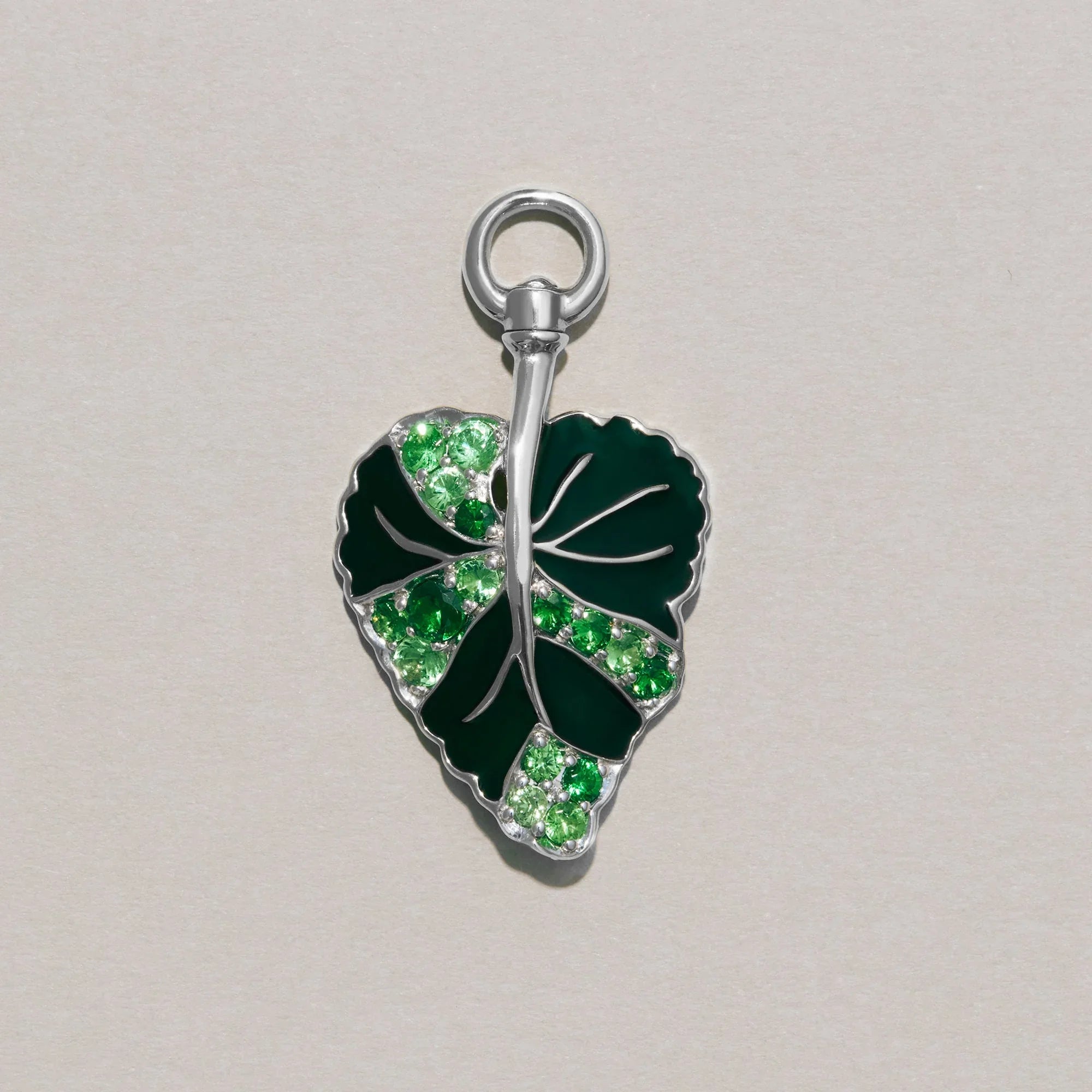 Green leaf-shaped pendant with embedded stones on a light gray background