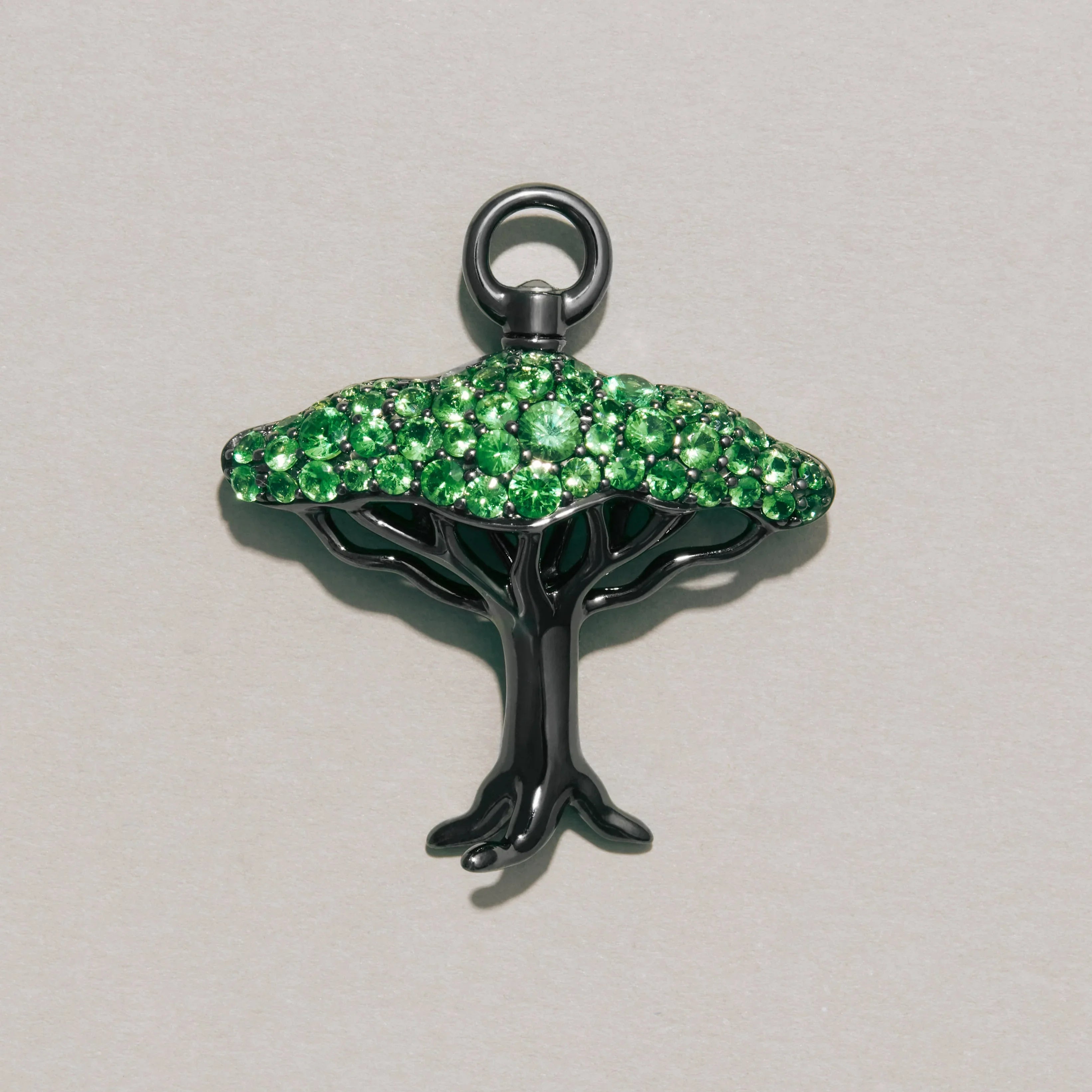 Tree-shaped pendant with green gemstones on a gray background