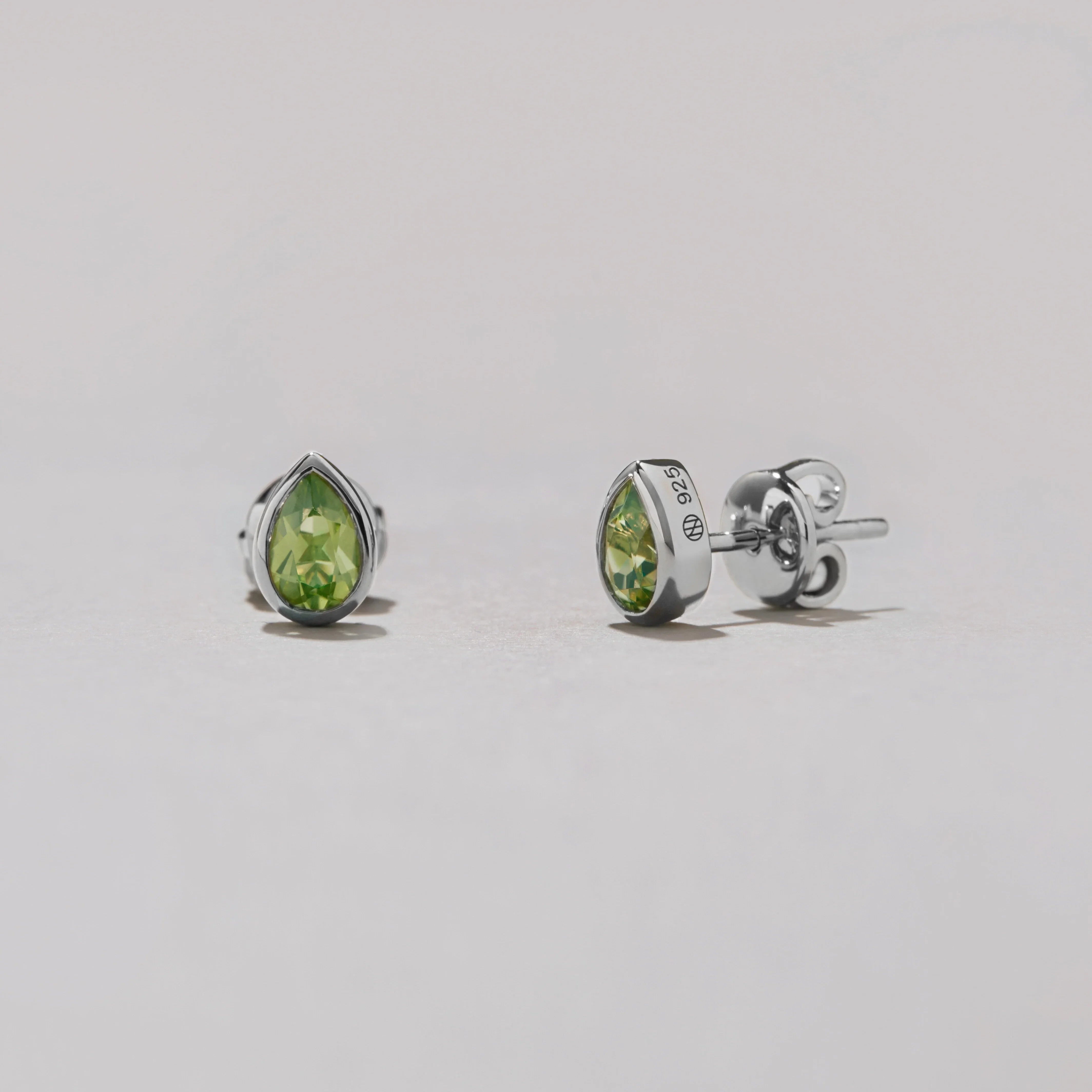 Pear-shaped green gemstone earrings on a light gray background