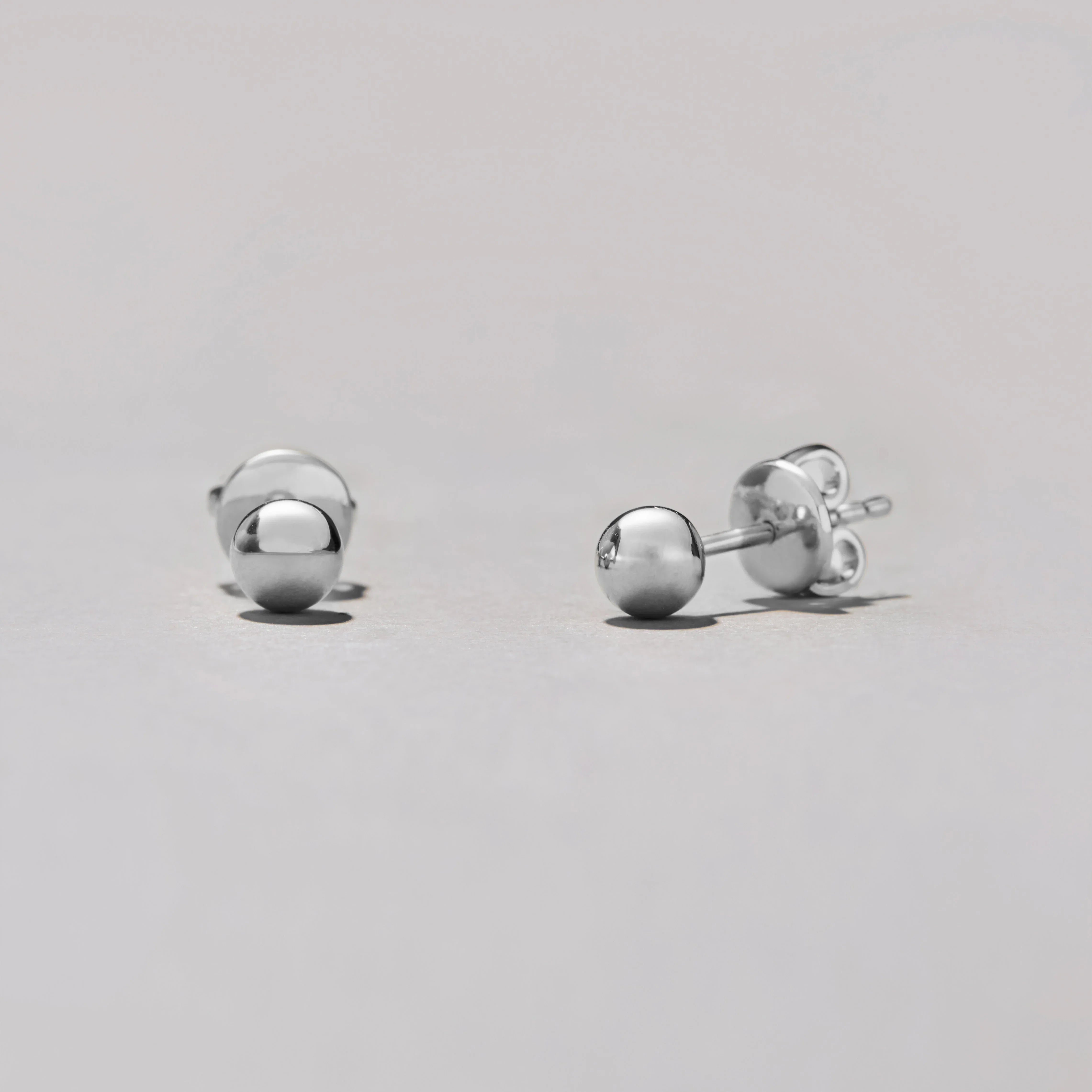 Pair of silver ball earrings on a light gray background