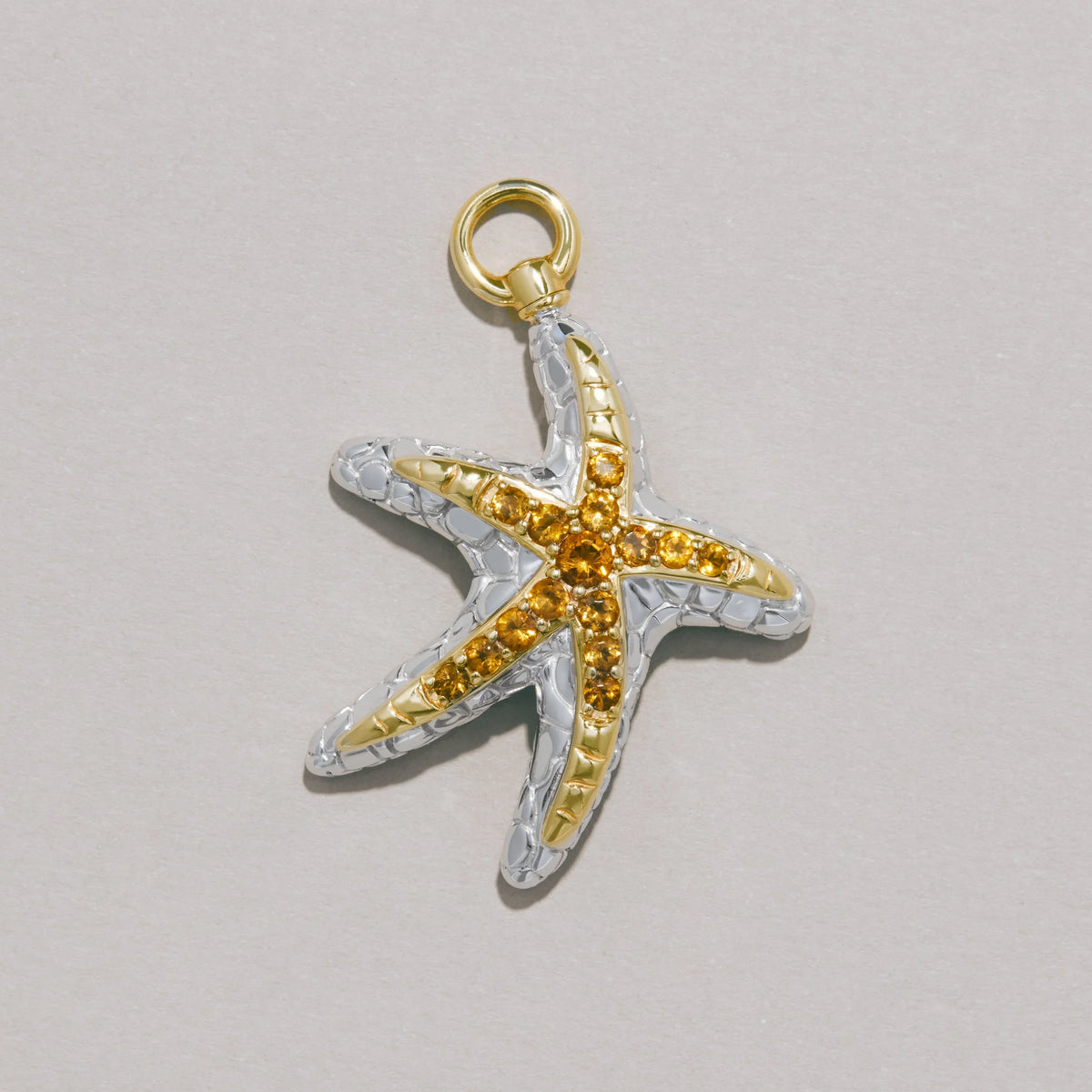 Silver and gold starfish charm adorned with yellow gemstones.