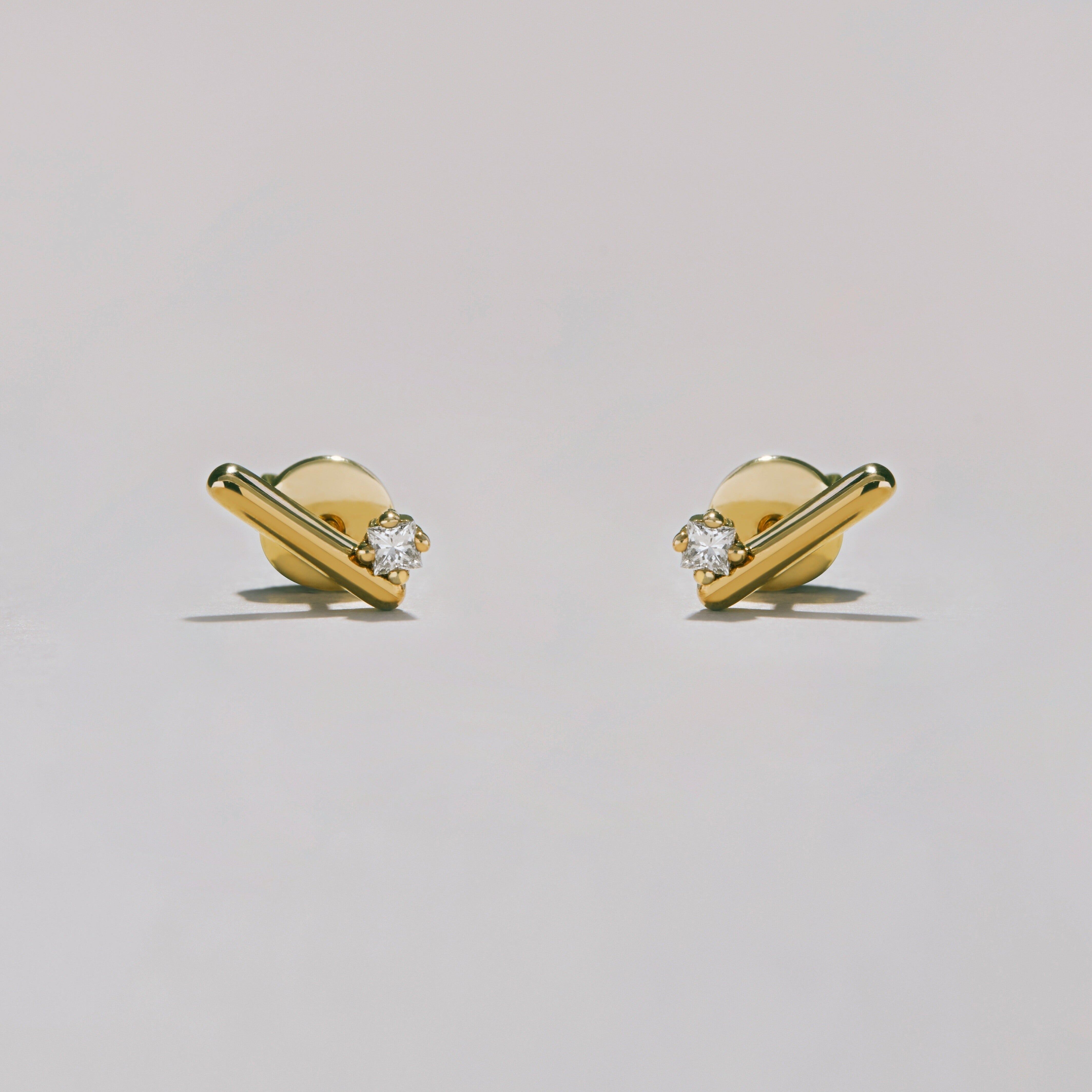 Gold earrings with diamond studs on a light gray background