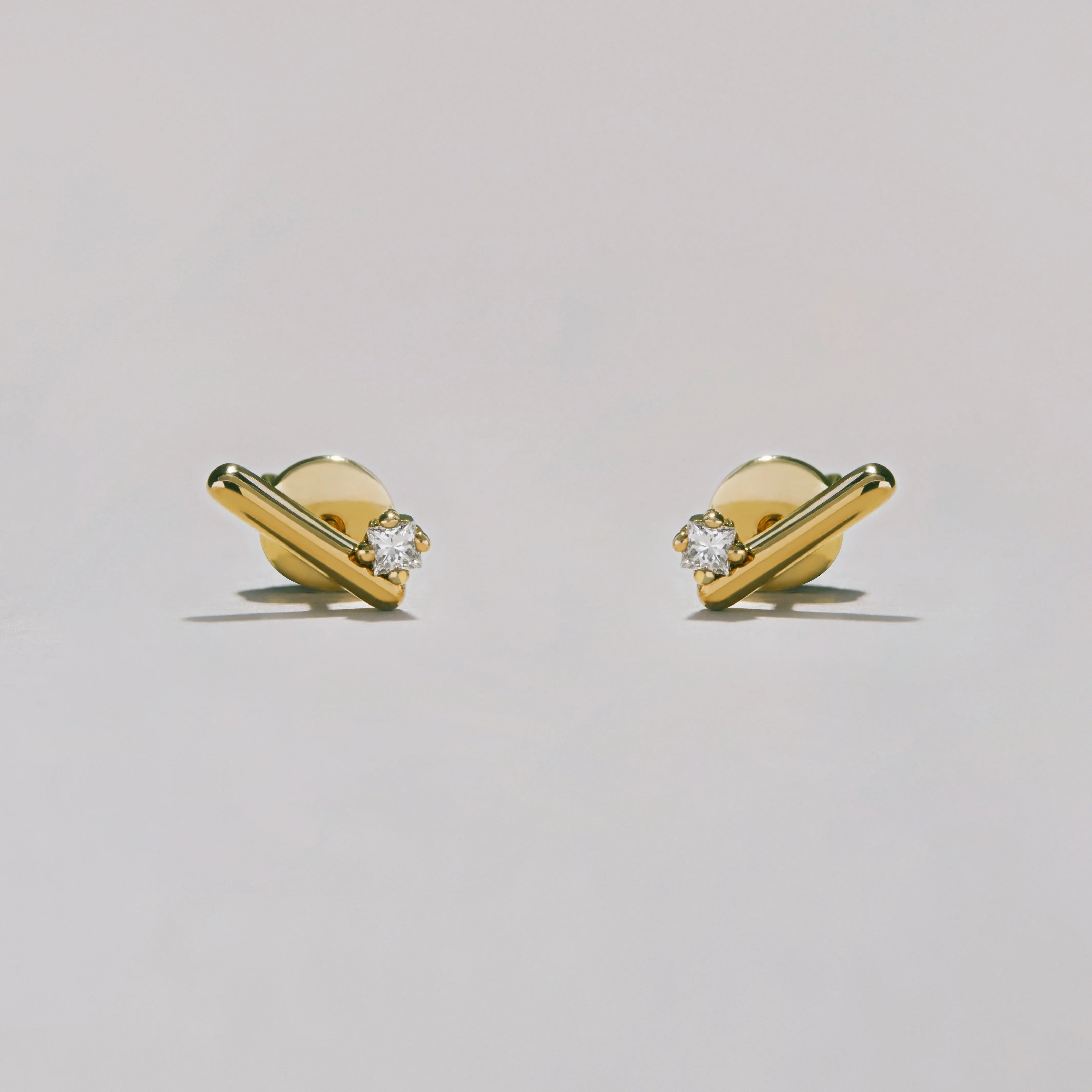 Gold earrings with diamond studs on a light gray background