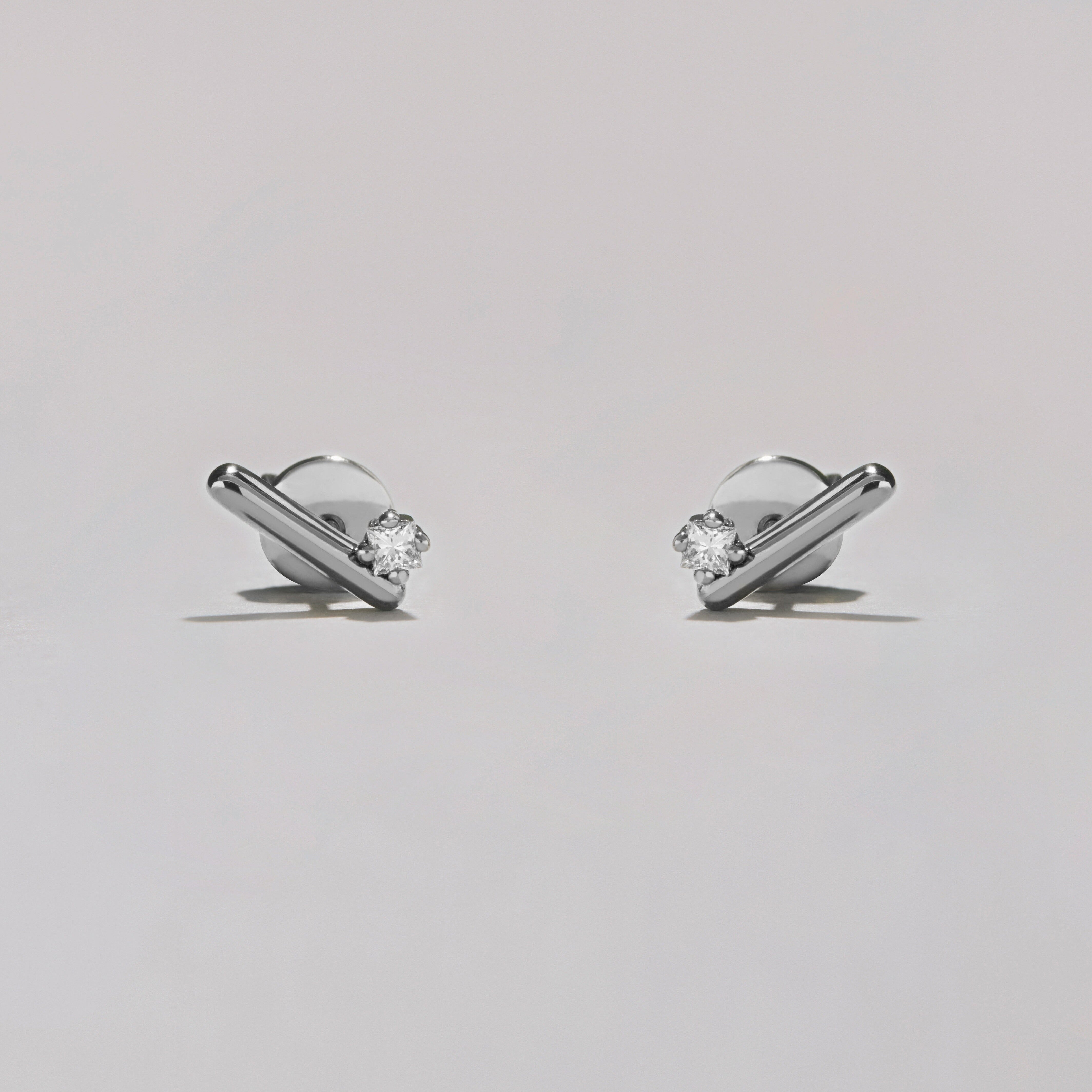 Pair of silver earrings with clear gemstones on a light gray background