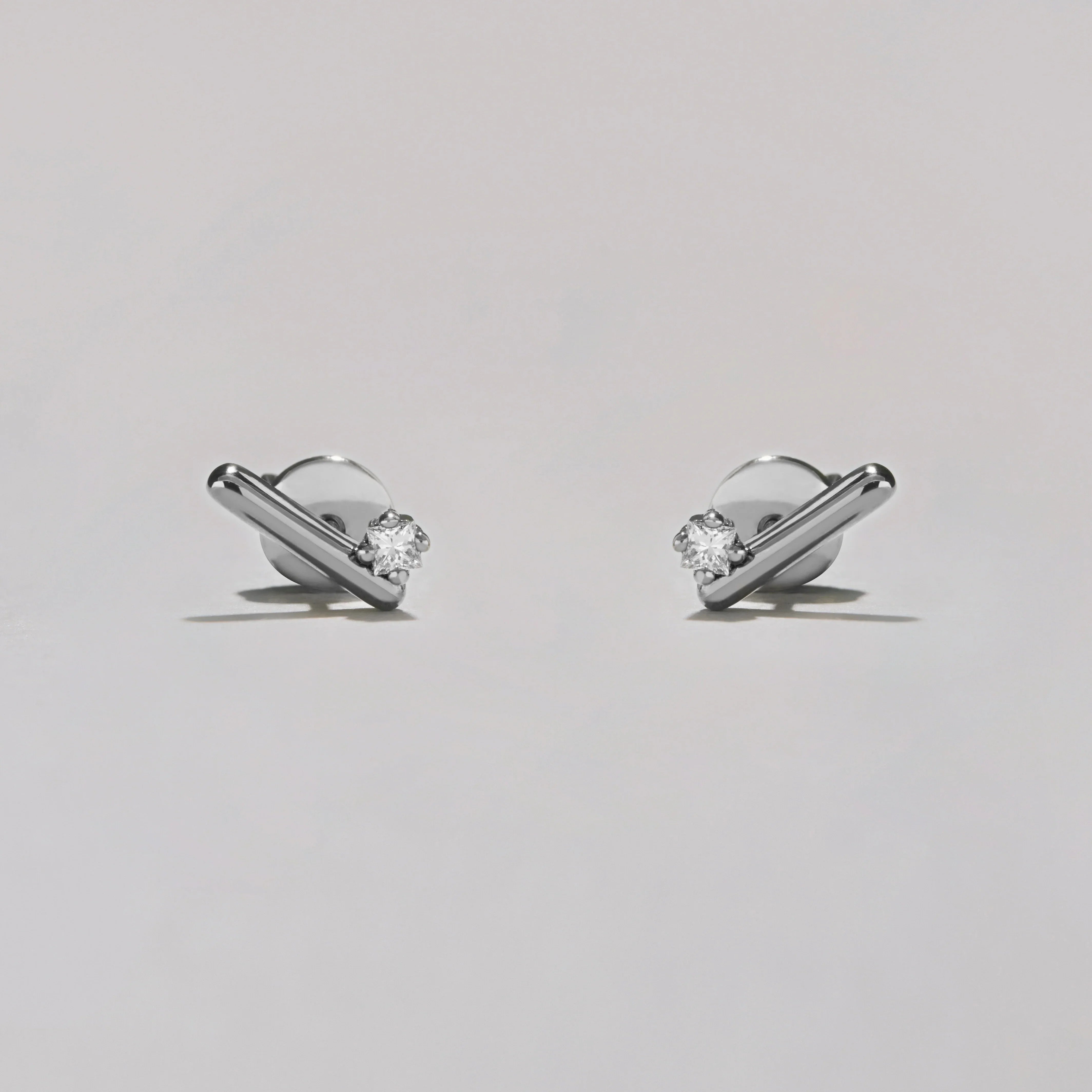 Pair of silver earrings with clear gemstones on a light gray background