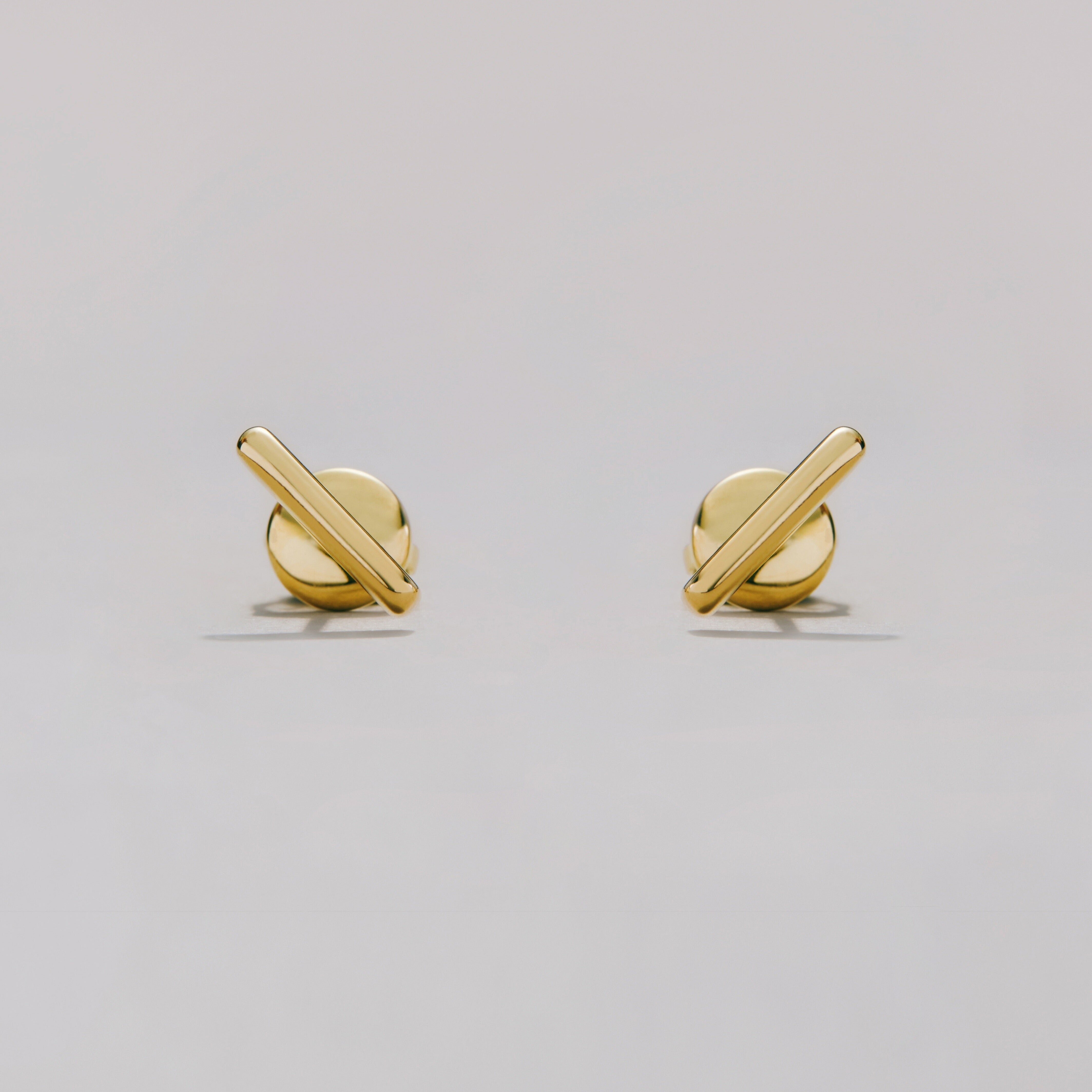 Pair of gold bar earrings on a light gray background