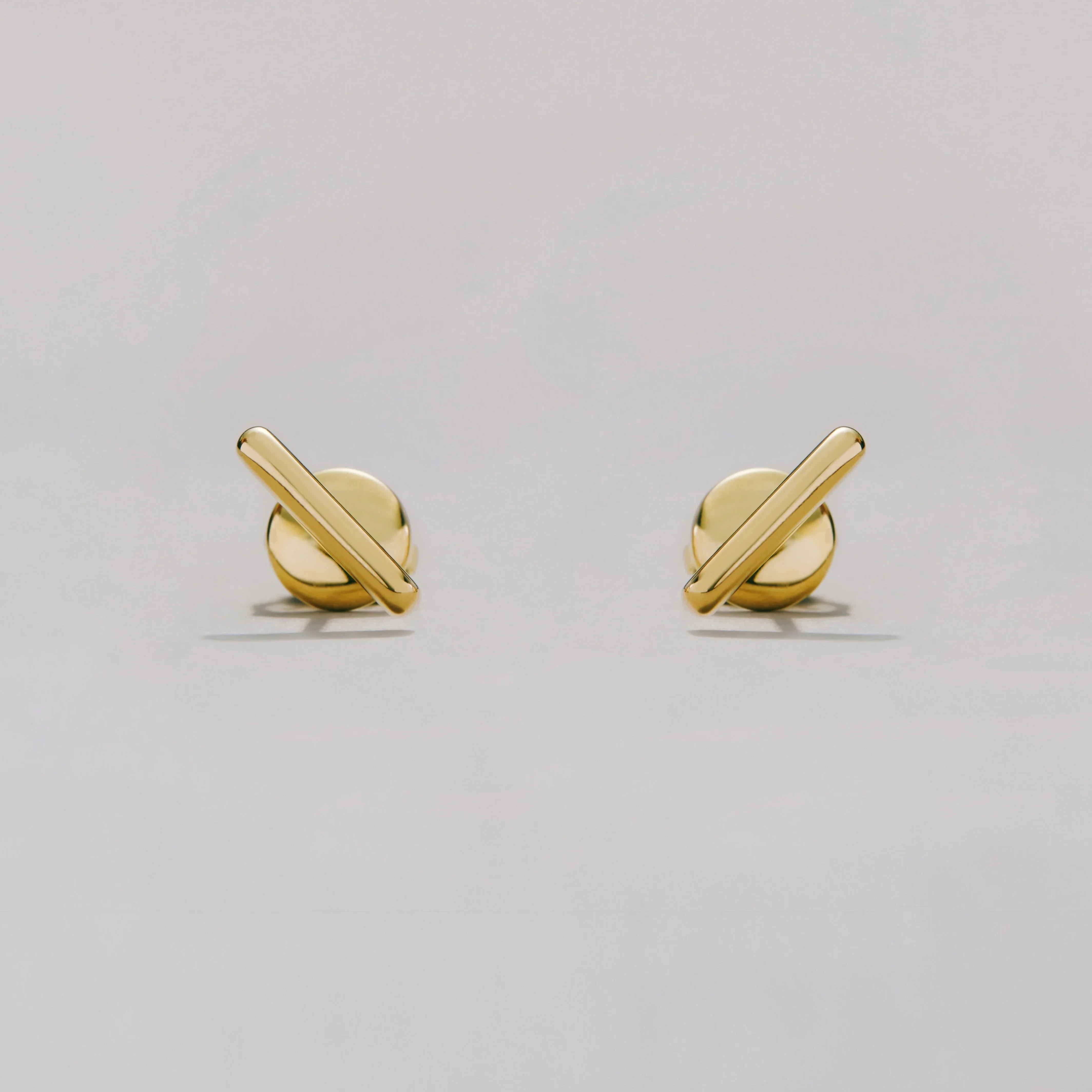 Pair of gold bar earrings on a light gray background