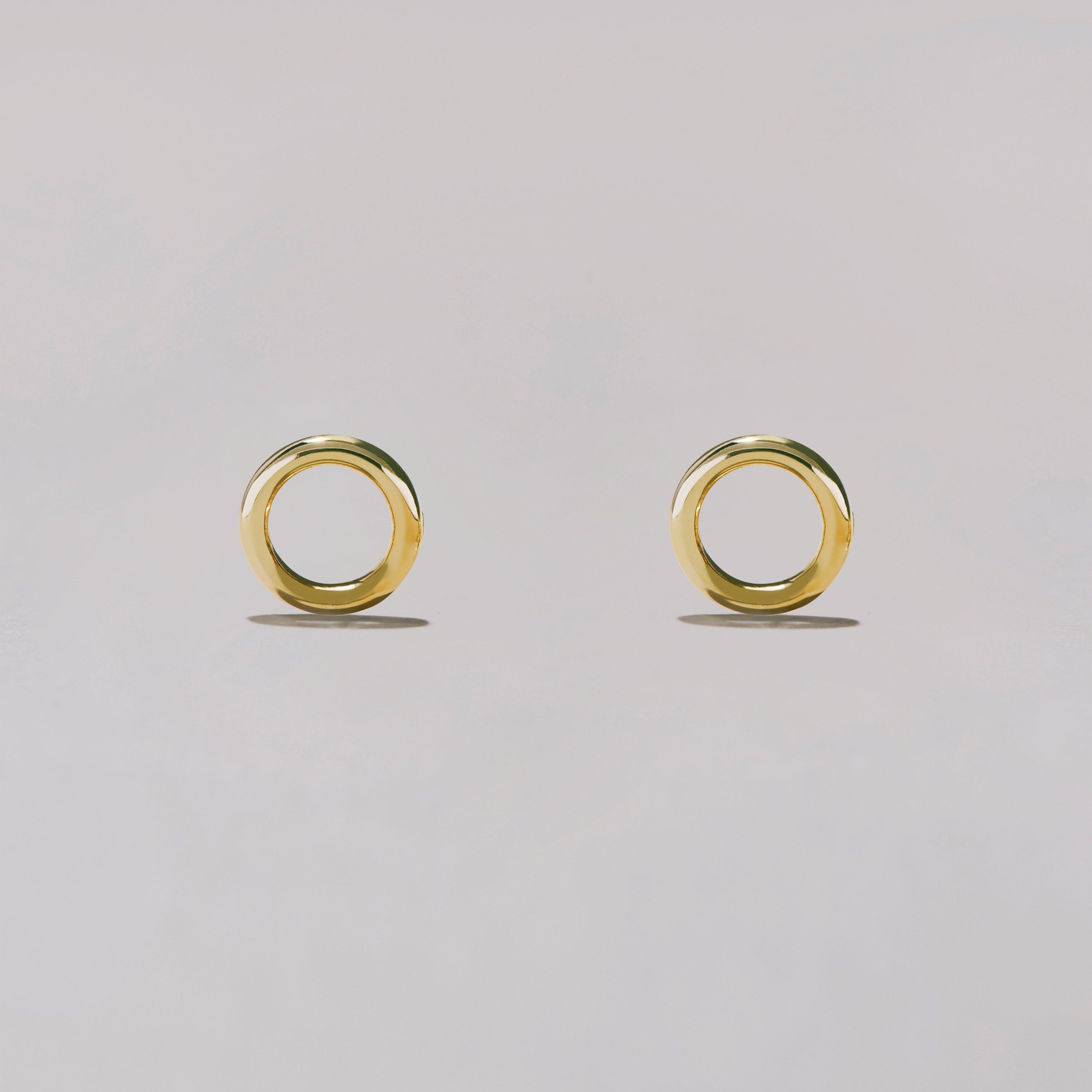 Gold circle earrings on a light gray background