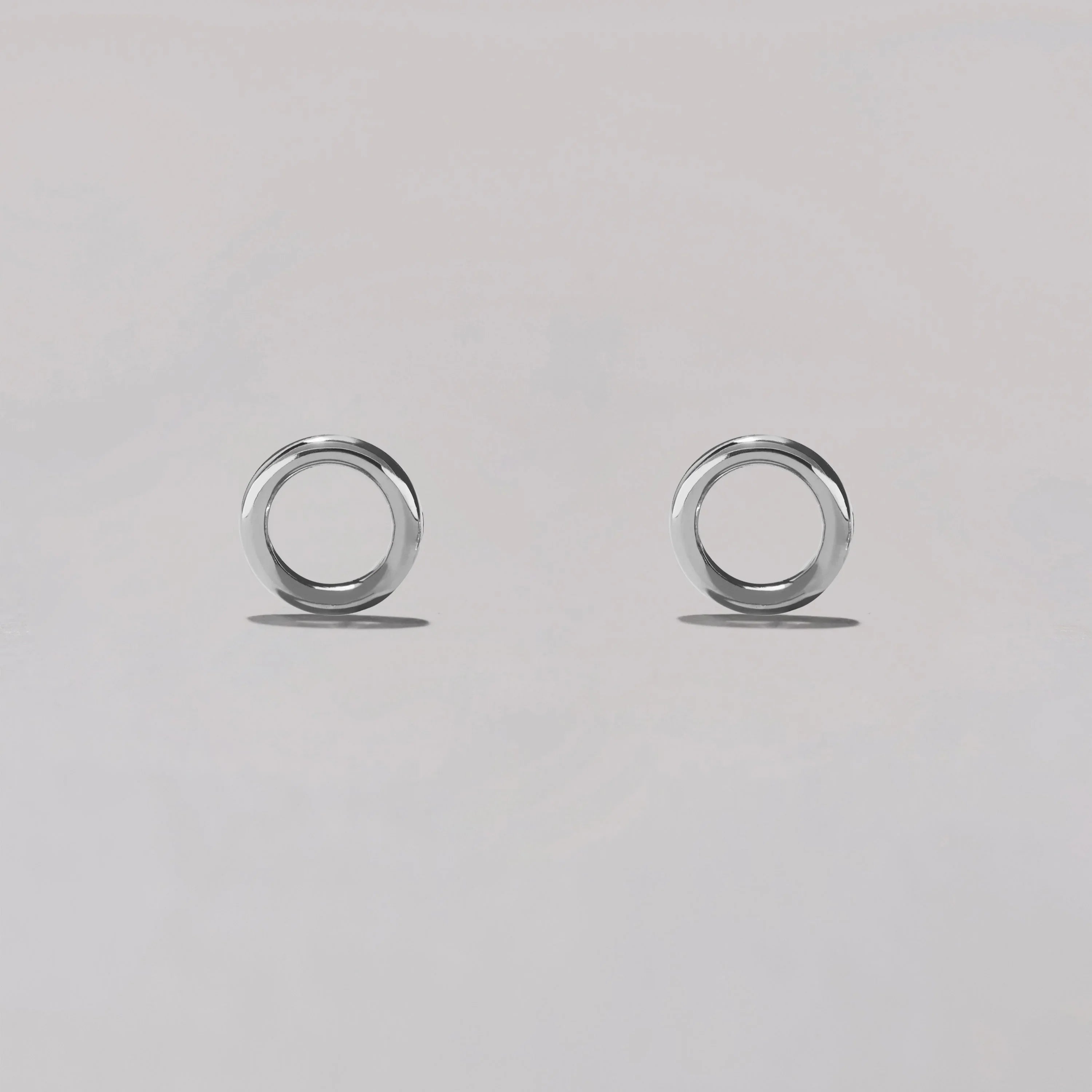 Pair of silver circular earrings on a light gray background