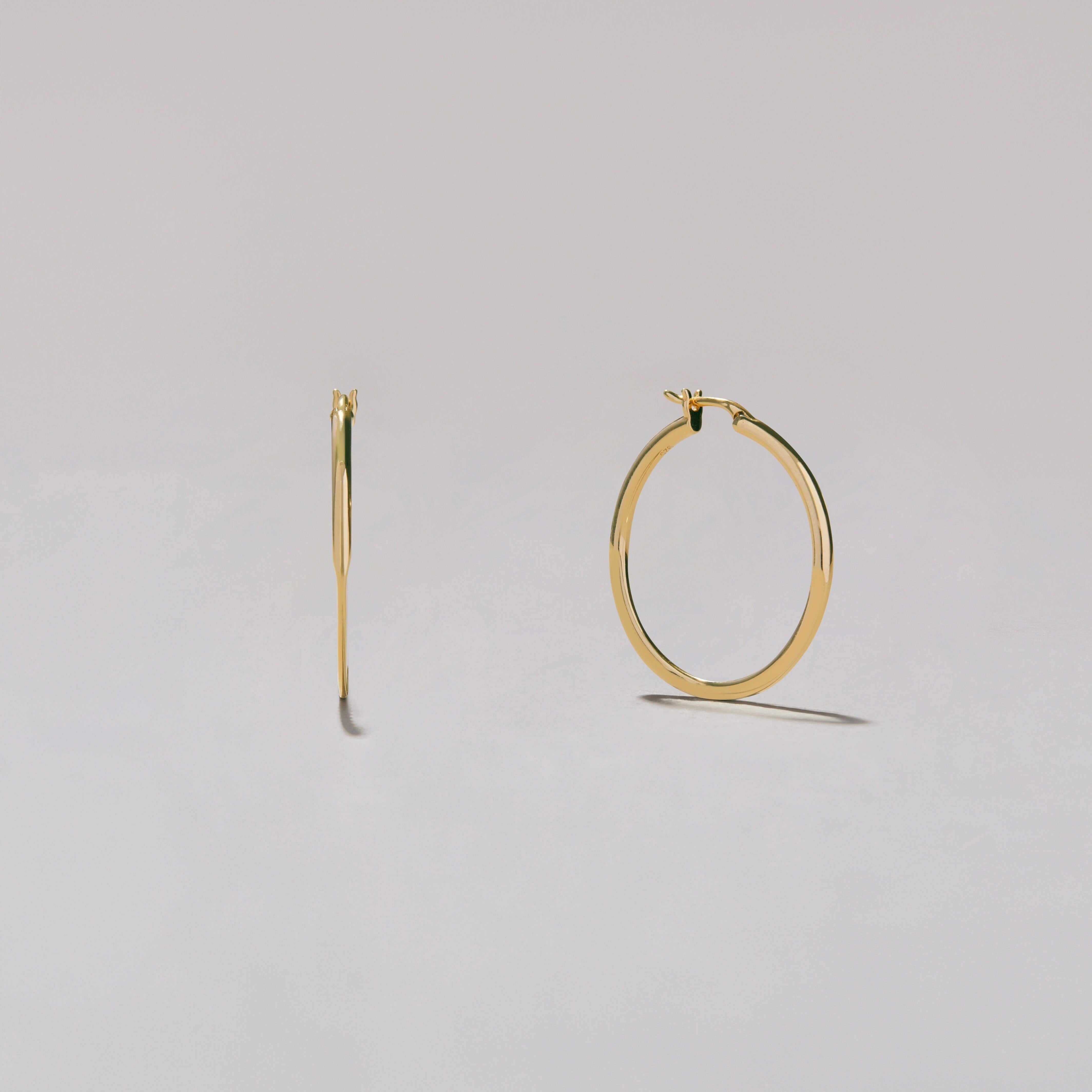 Gold hoop earrings on a light gray background