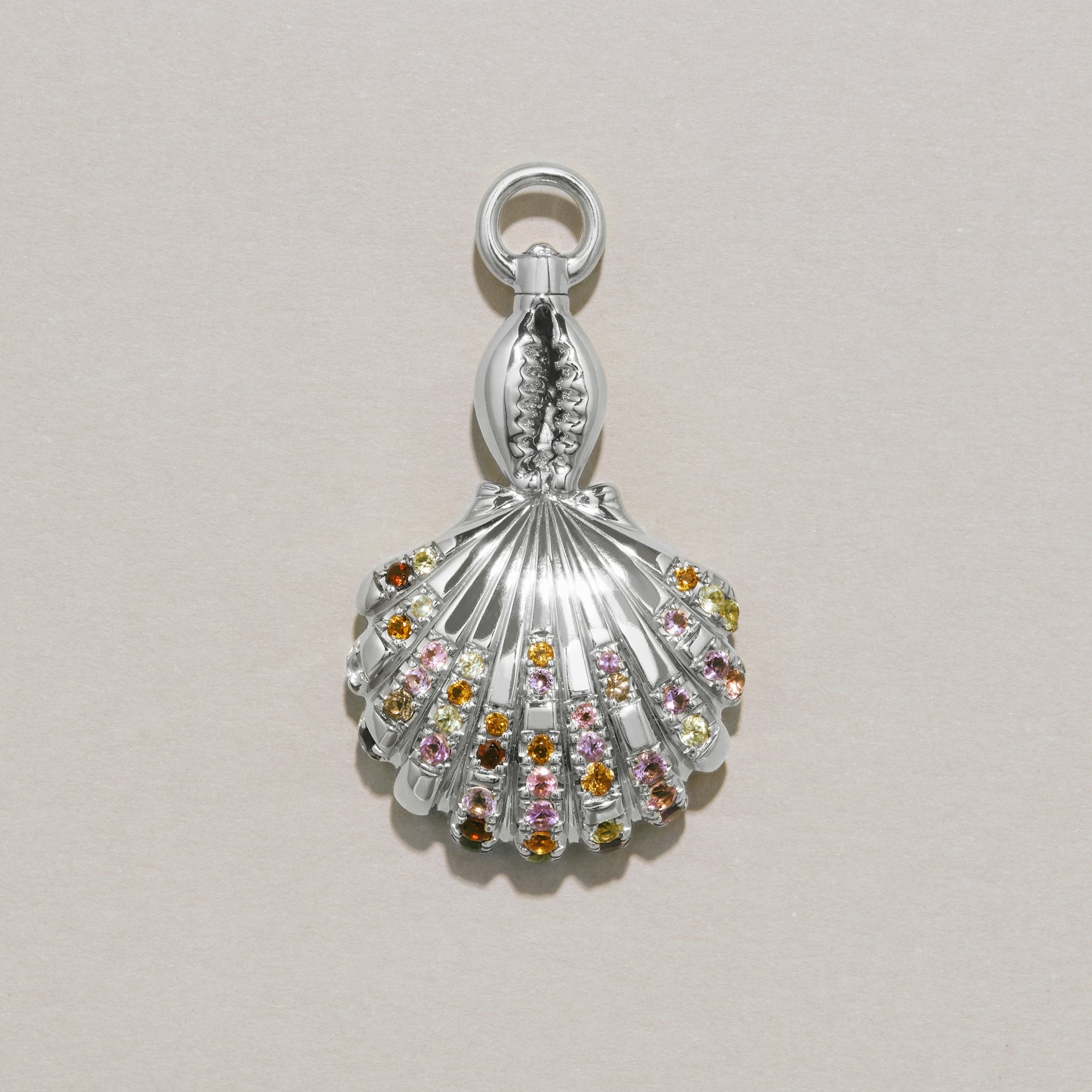 Silver shell charm with colorful stones on a light gray background
