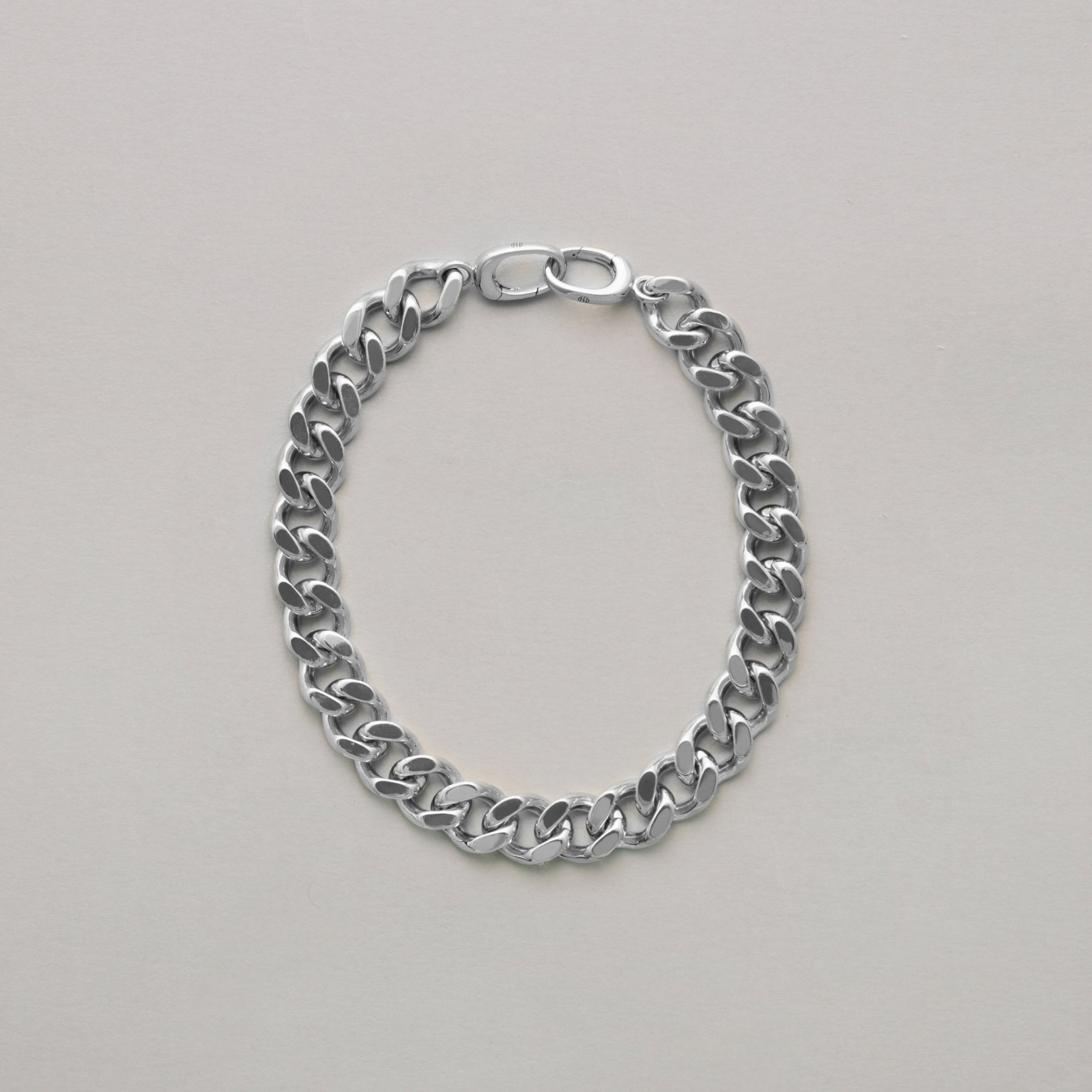 Classic sterling silver curb chain bracelet laid flat on light surface