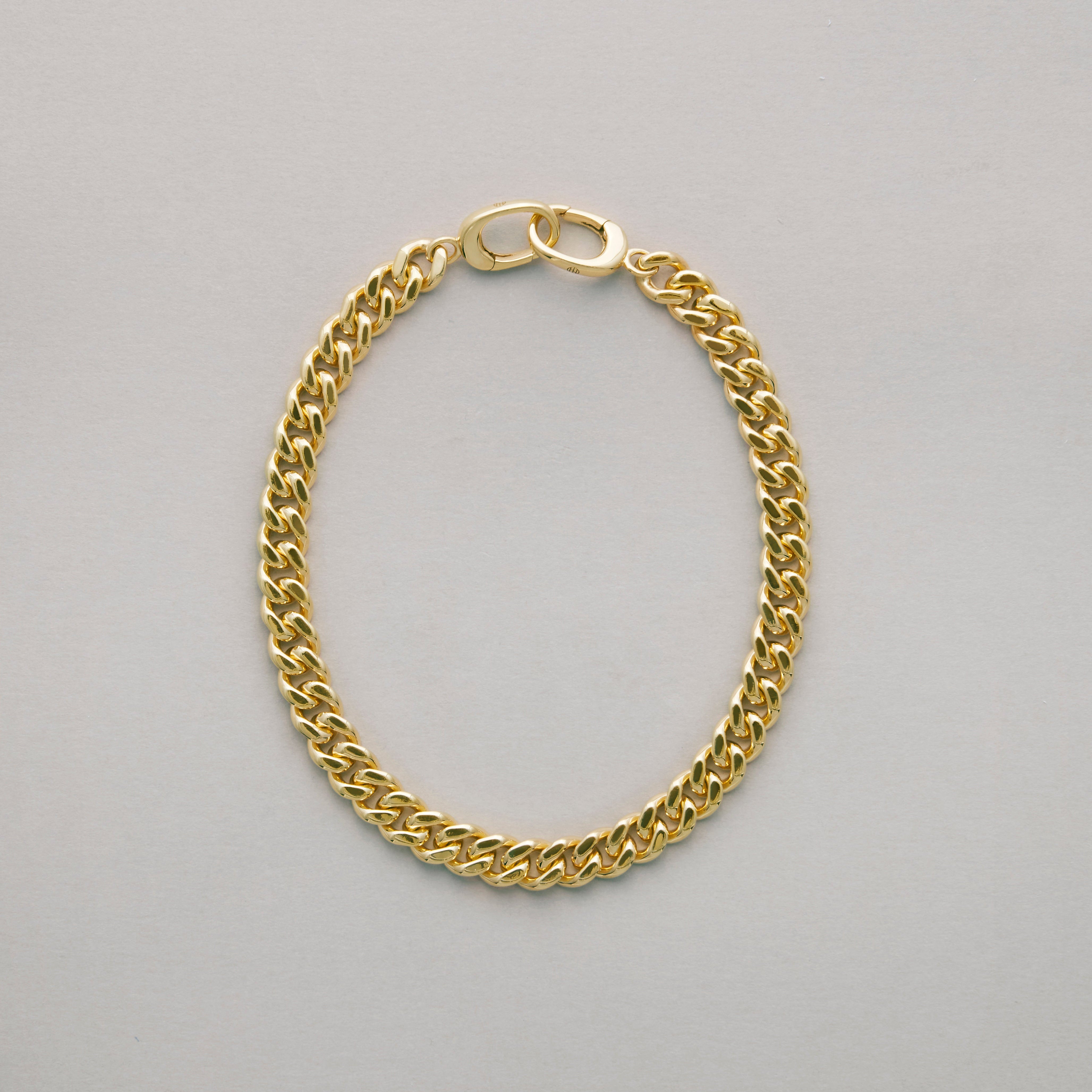 Close-up of classic gold Cuban link bracelet on plain background