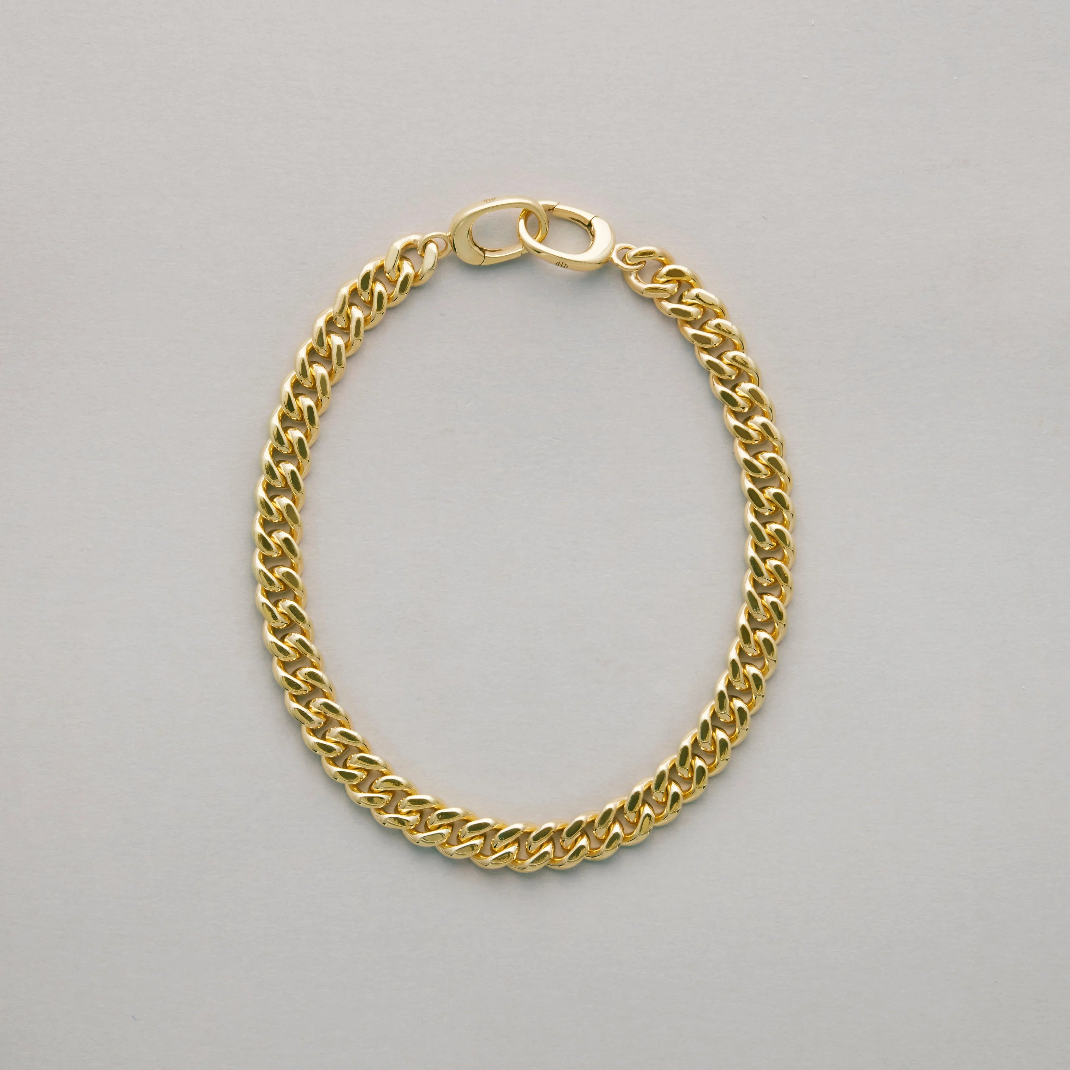 Close-up of classic gold Cuban link bracelet on plain background