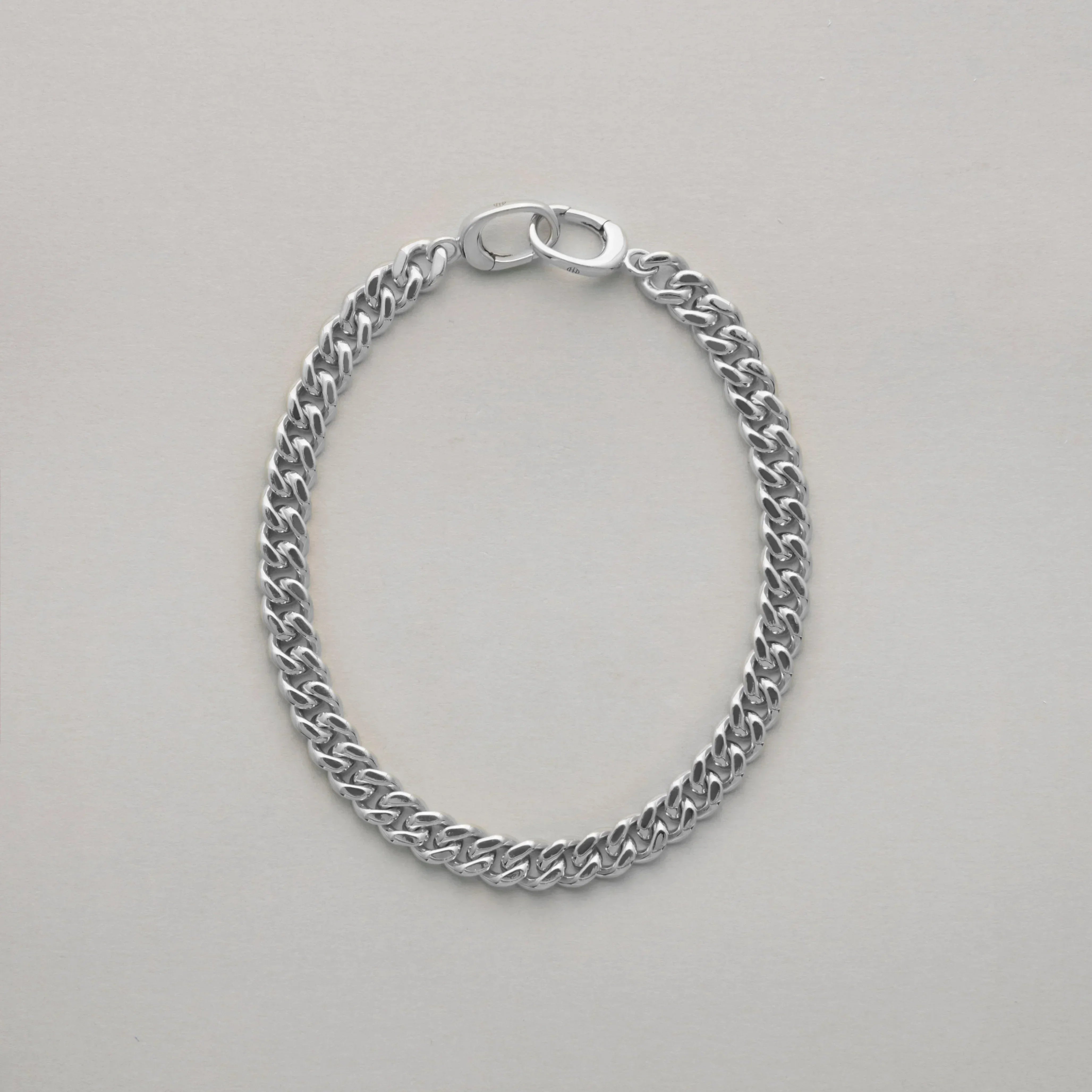 Close-up of classic silver Cuban link bracelet on plain background
