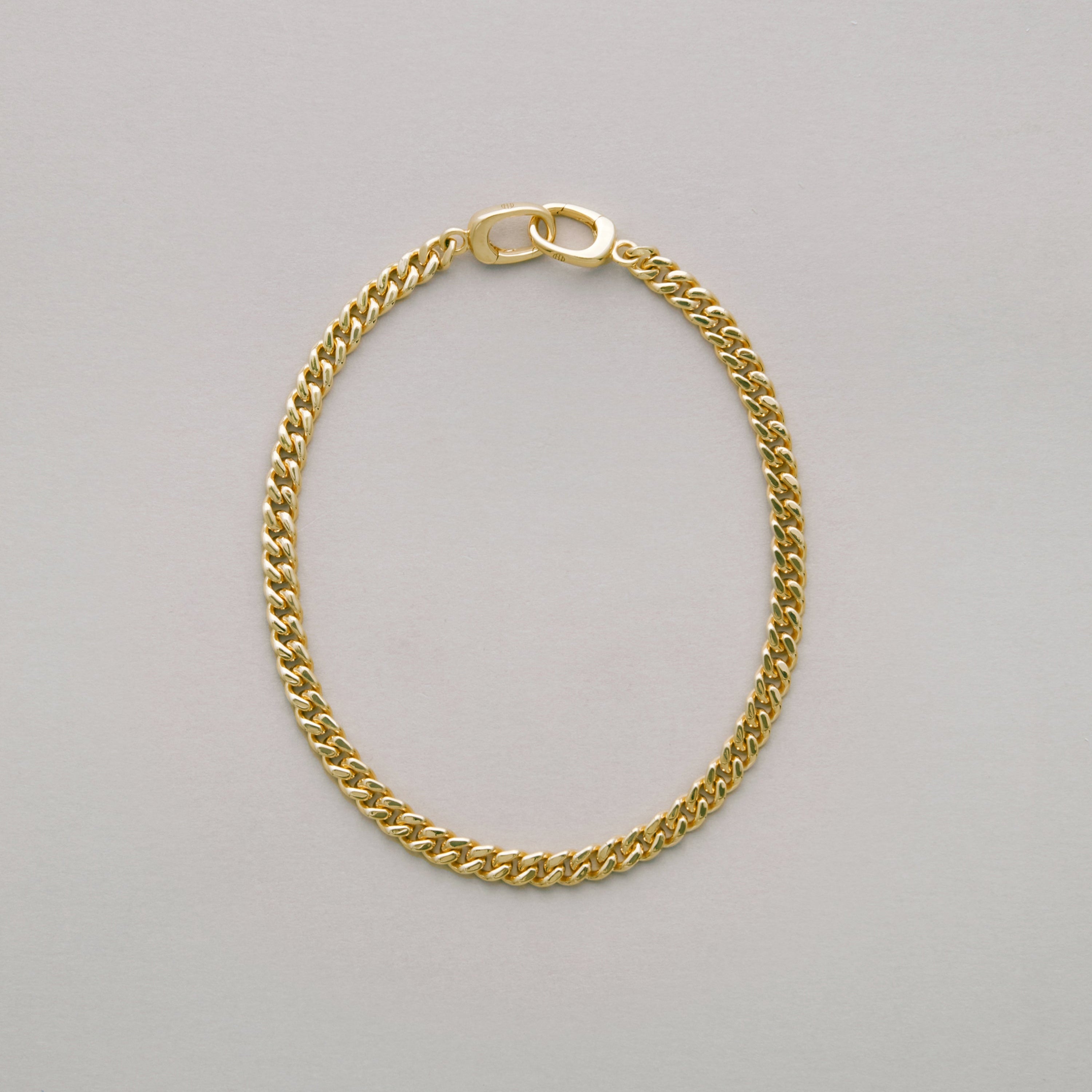 Gold chain bracelet on a light gray background
