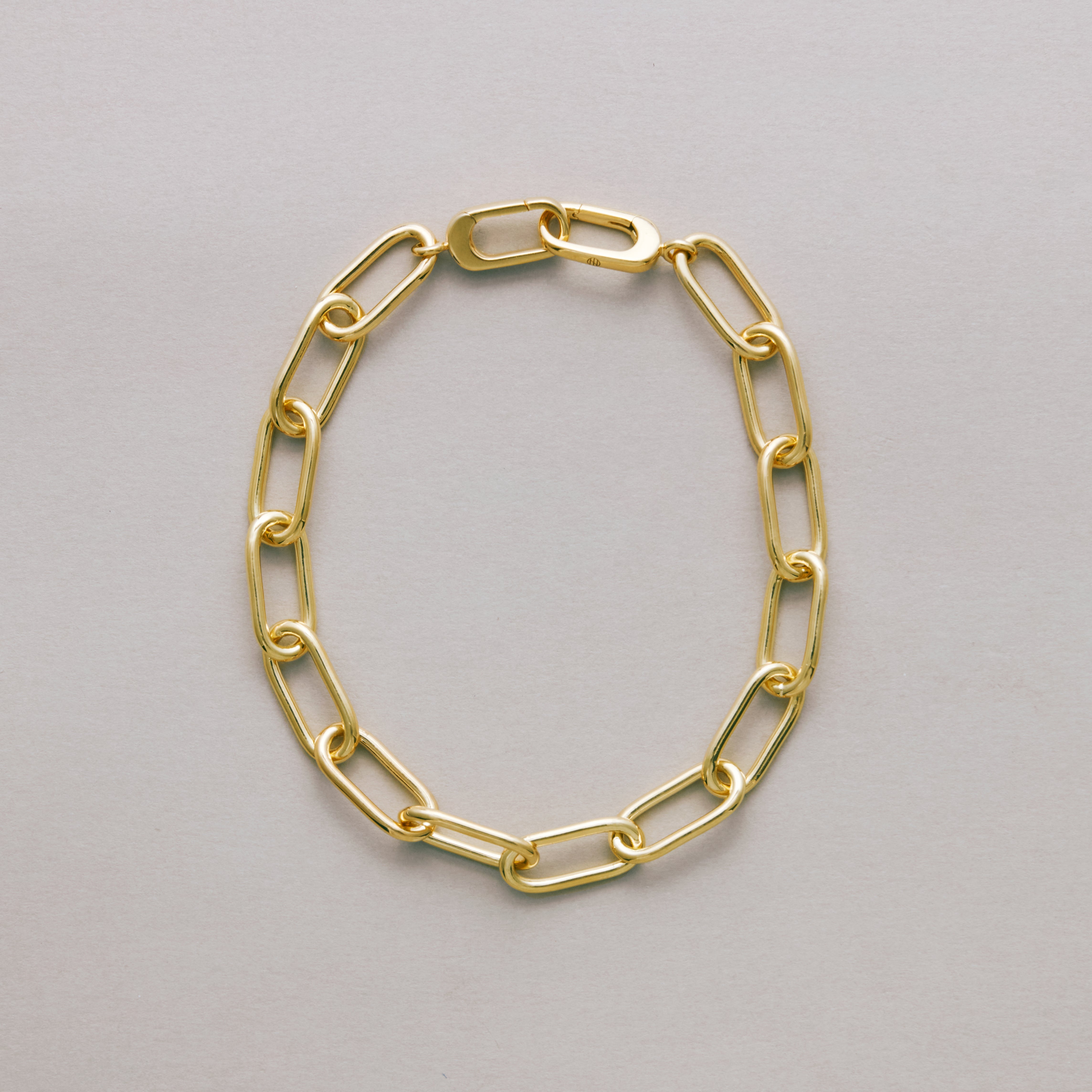 Gold paperclip chain bracelet on a gray background