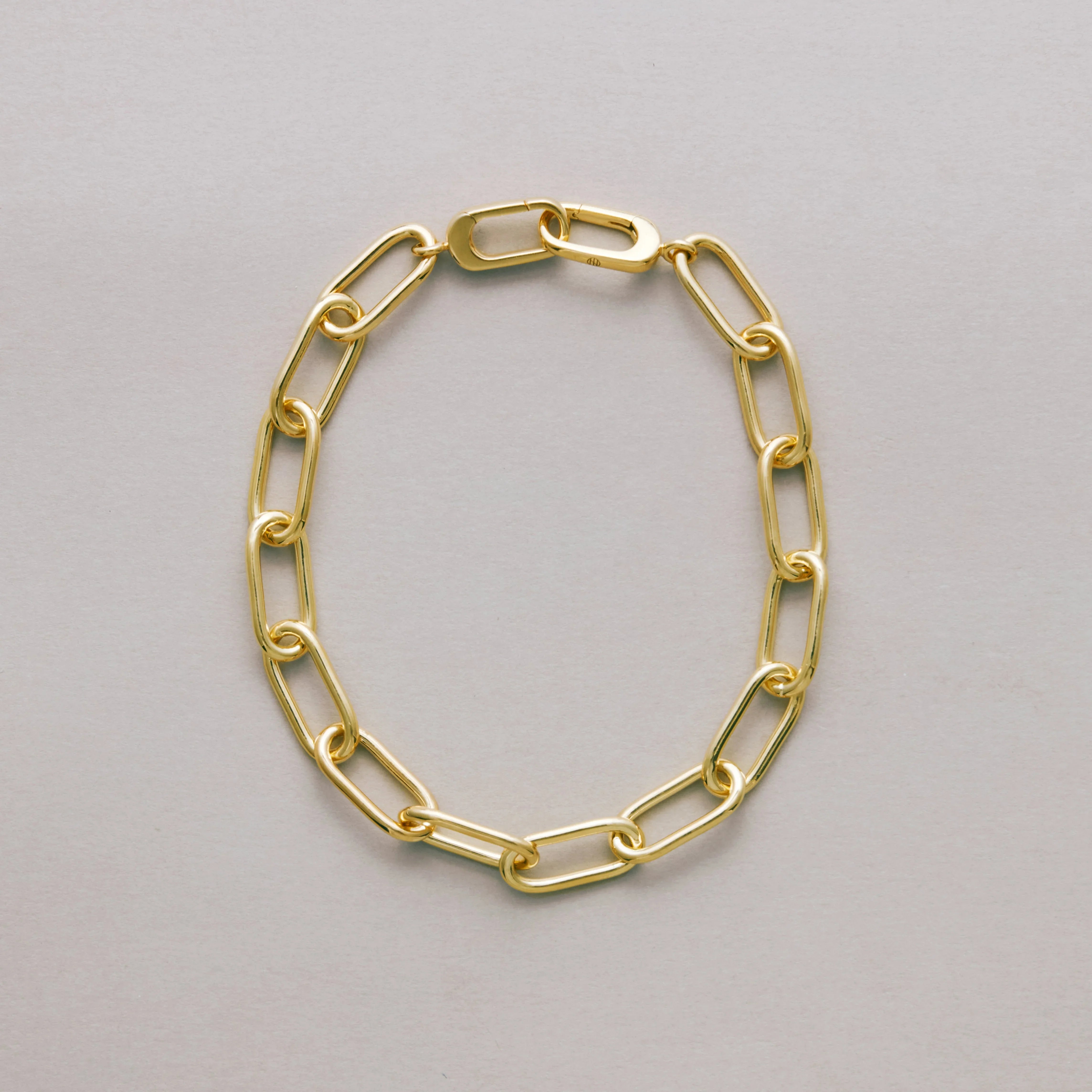 Gold paperclip chain bracelet on a gray background