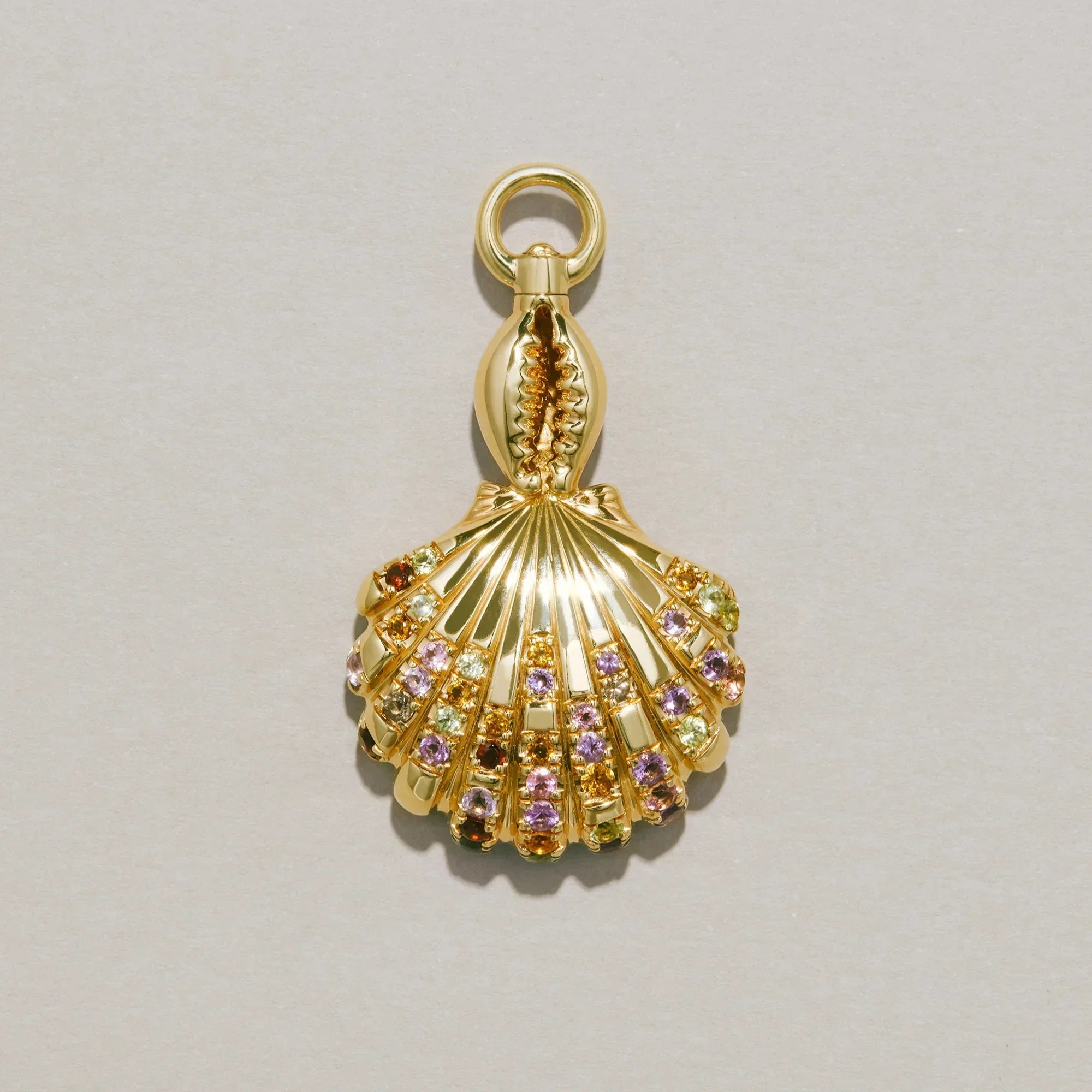 Gold shell-shaped charm with colorful stones on a light gray background